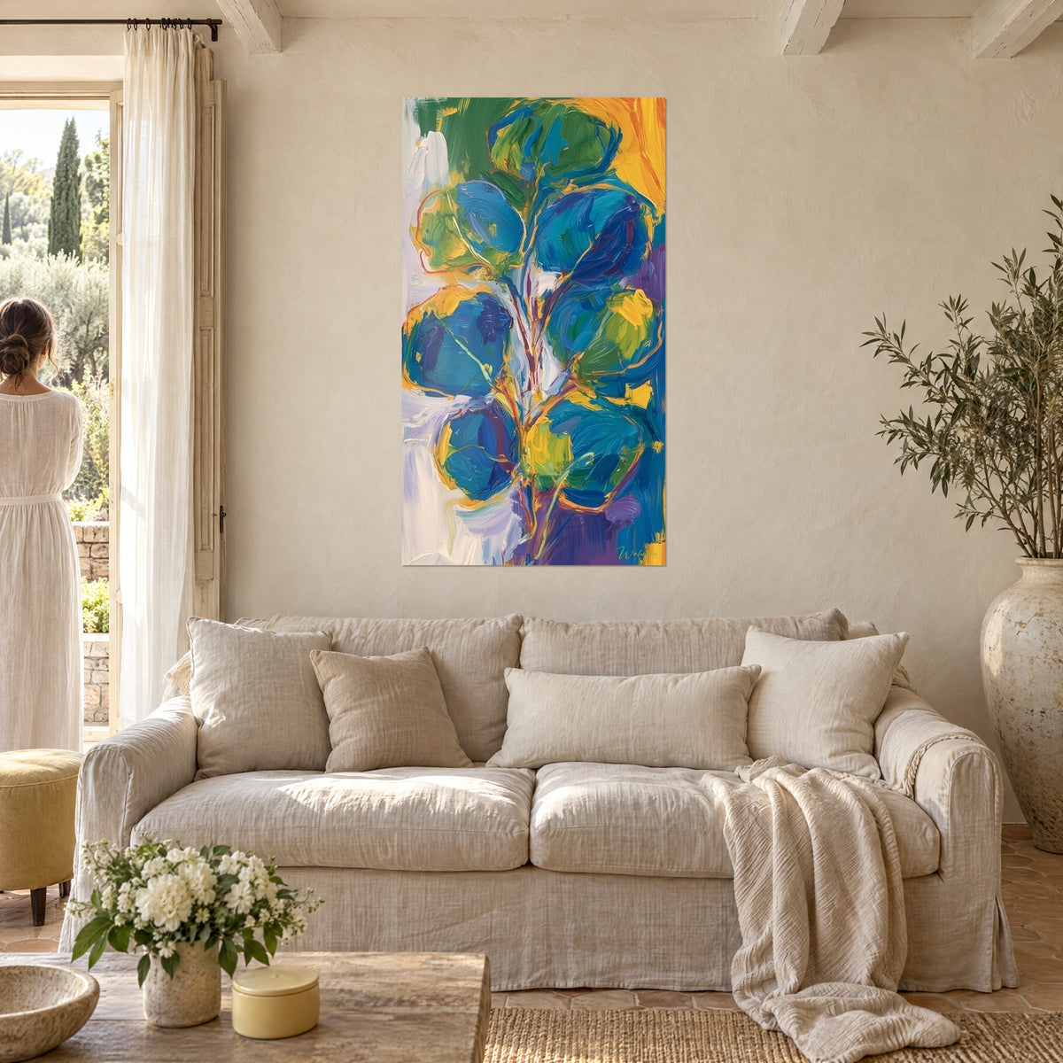 Tableau branche d'eucalyptus aux feuilles rondes bleu cobalt et vert tilleul, tige orangée, au-dessus d'un canapé dans un salon lumineux