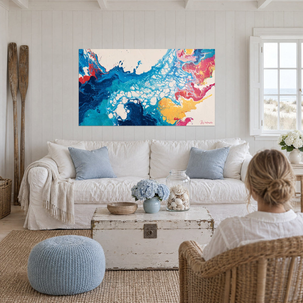 Quadro esplosione di blu turchese e rosa fucsia, schiuma bianca a cellule, donna di spalle, sopra un divano in un soggiorno luminoso