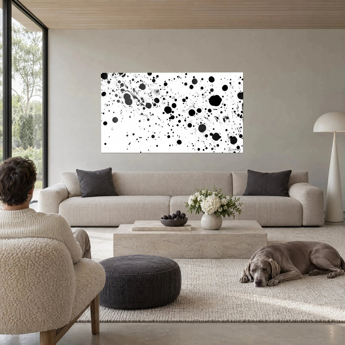 Cuadro de gotas de tinta negra salpicando un fondo blanco, tonos grises, sobre un sofá en un salón luminoso