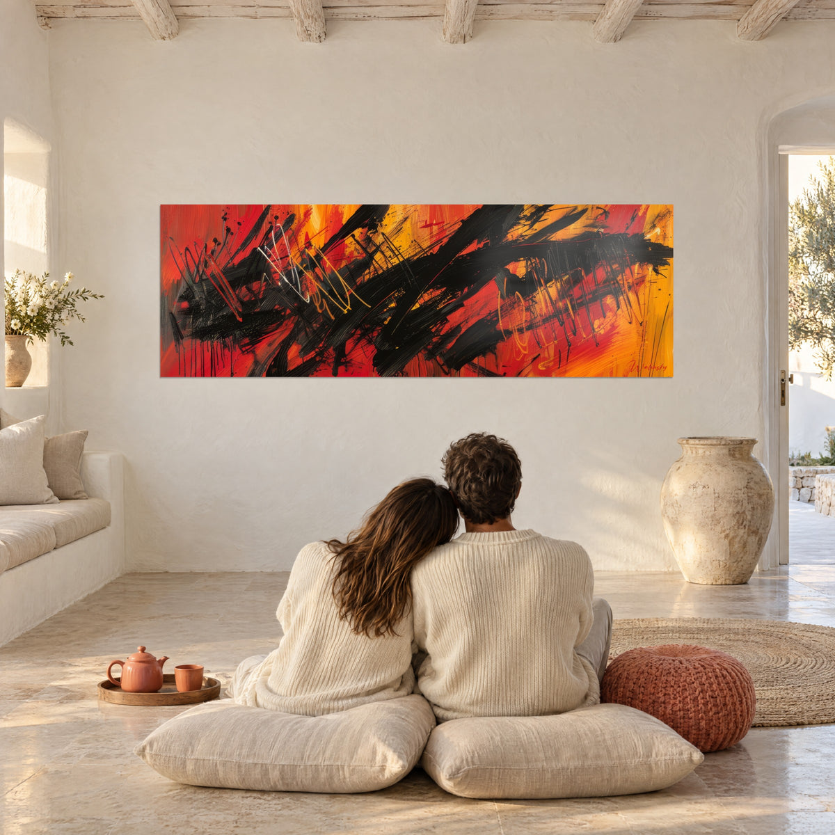 Panoramisch wandschilderij van zwarte penseelstreken, vuurrood en zonnig oranje, bekeken door een omhelsd stel op witte kussens