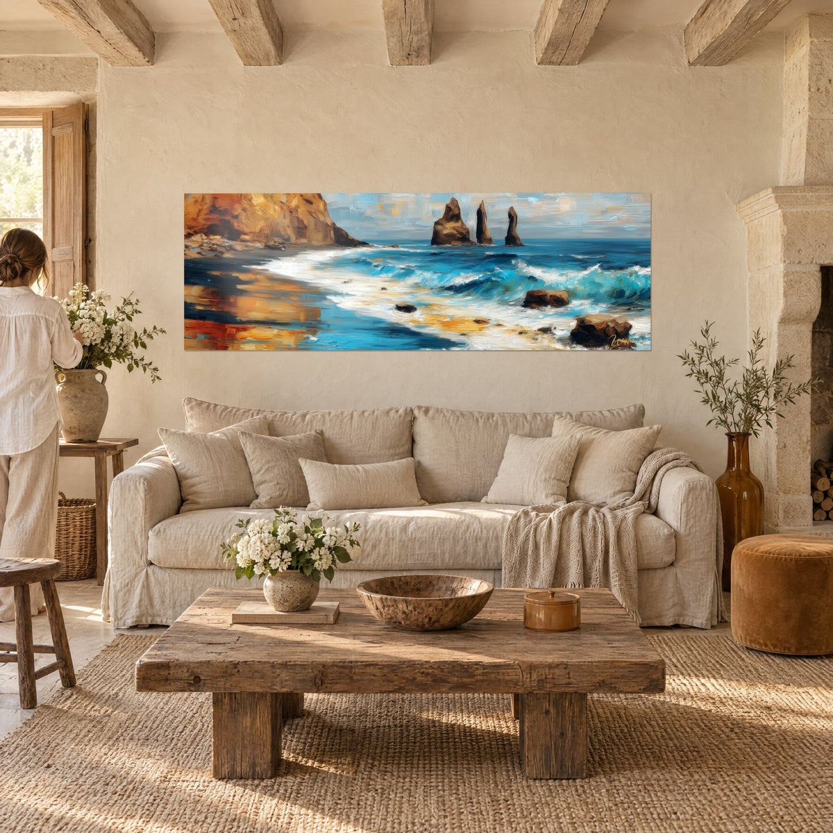 Wall art ochre cliffs overlooking a turquoise sea, three jagged rock spires, woman seen from behind, above a sofa in a bright living room
