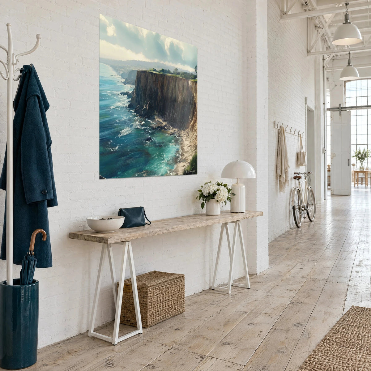 Wall art of an ochre rock face overlooking blue-green waves, grassy summit, hung in a loft corridor with large windows
