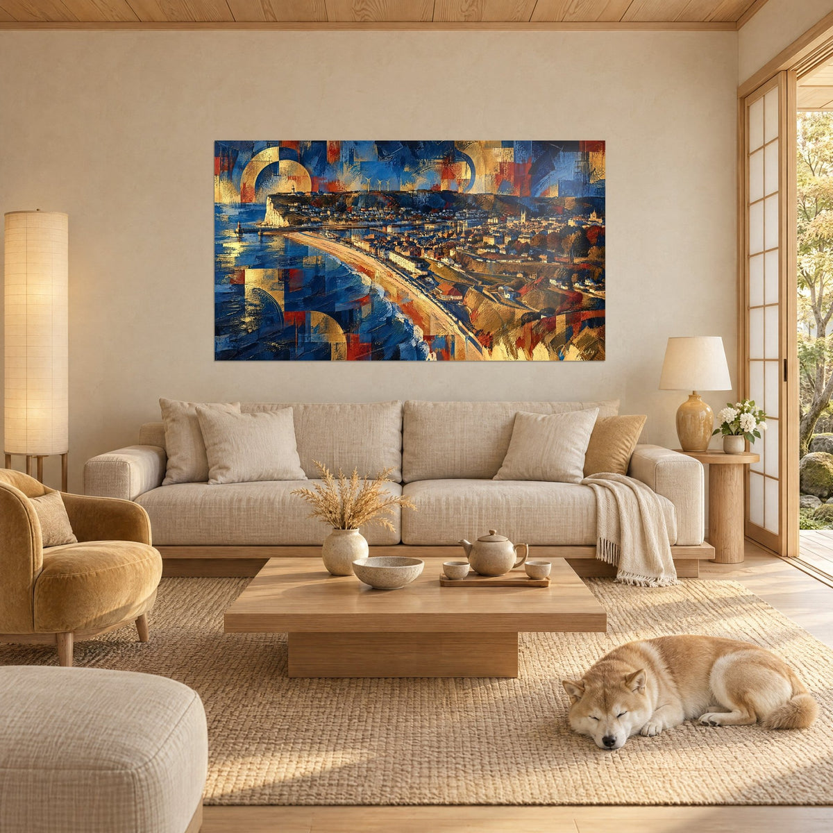Wall art aerial view of Fécamp in navy blue and gold, white cliff and curving beach, sleeping Shiba, above a sofa in a bright living room