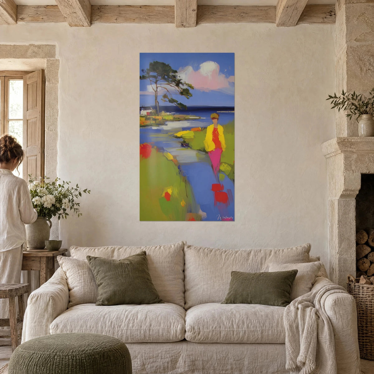Tableau promeneuse en veste jaune et pantalon rose longeant un bras de mer bleu, pin penché, au-dessus d'un canapé dans un salon lumineux