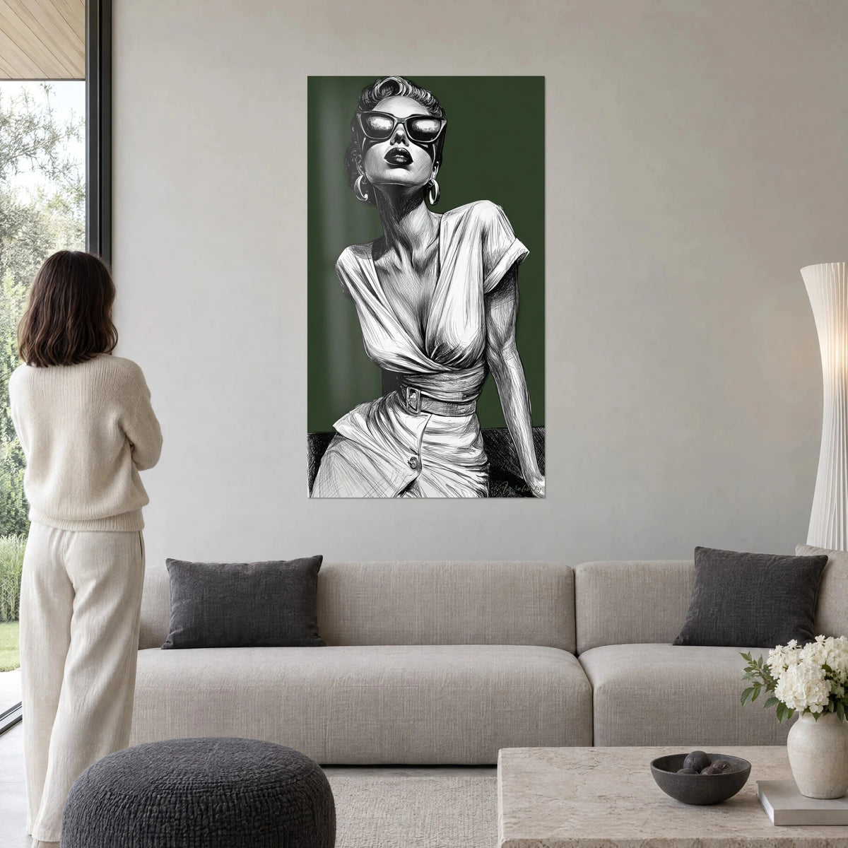 Tableau élégante aux lunettes papillon et boucles créoles, encre noir et blanc sur fond vert sapin, au-dessus d'un canapé dans un salon lumineux