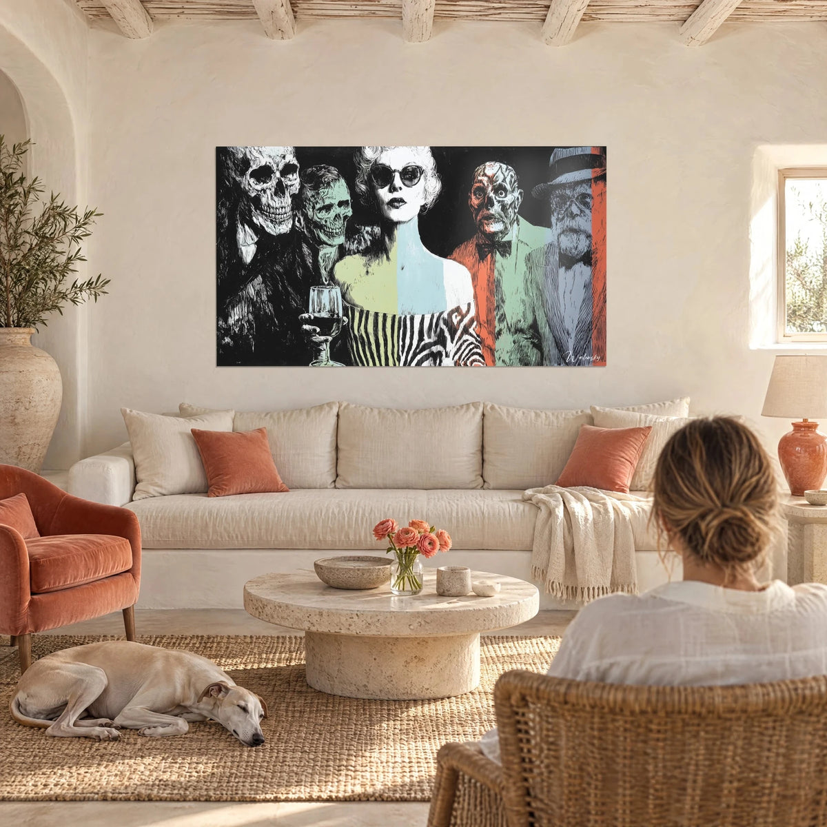 Cuadro mujer con gafas de sol negras rodeada de calaveras y rostros verdosos, negro y coral, encima de un sofá en un salón luminoso