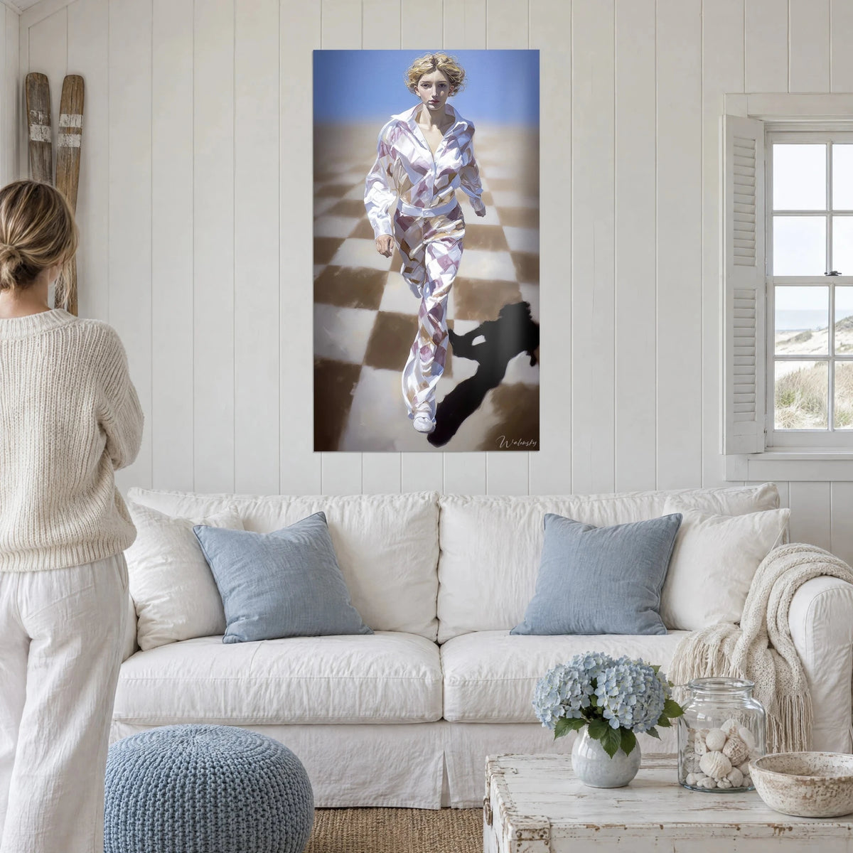 Schilderij jonge blonde vrouw in wit pak met mauve ruiten, loopt over een bruin en crème geblokte vloer, boven een bank in een lichte woonkamer