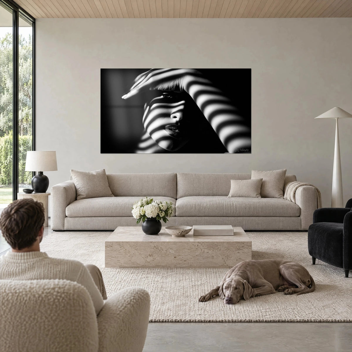 Gemälde weibliches Porträt mit gestreiften Schatten, Gesicht in Schwarzweiß, Hand an der Stirn, über einem Sofa in einem hellen Wohnzimmer