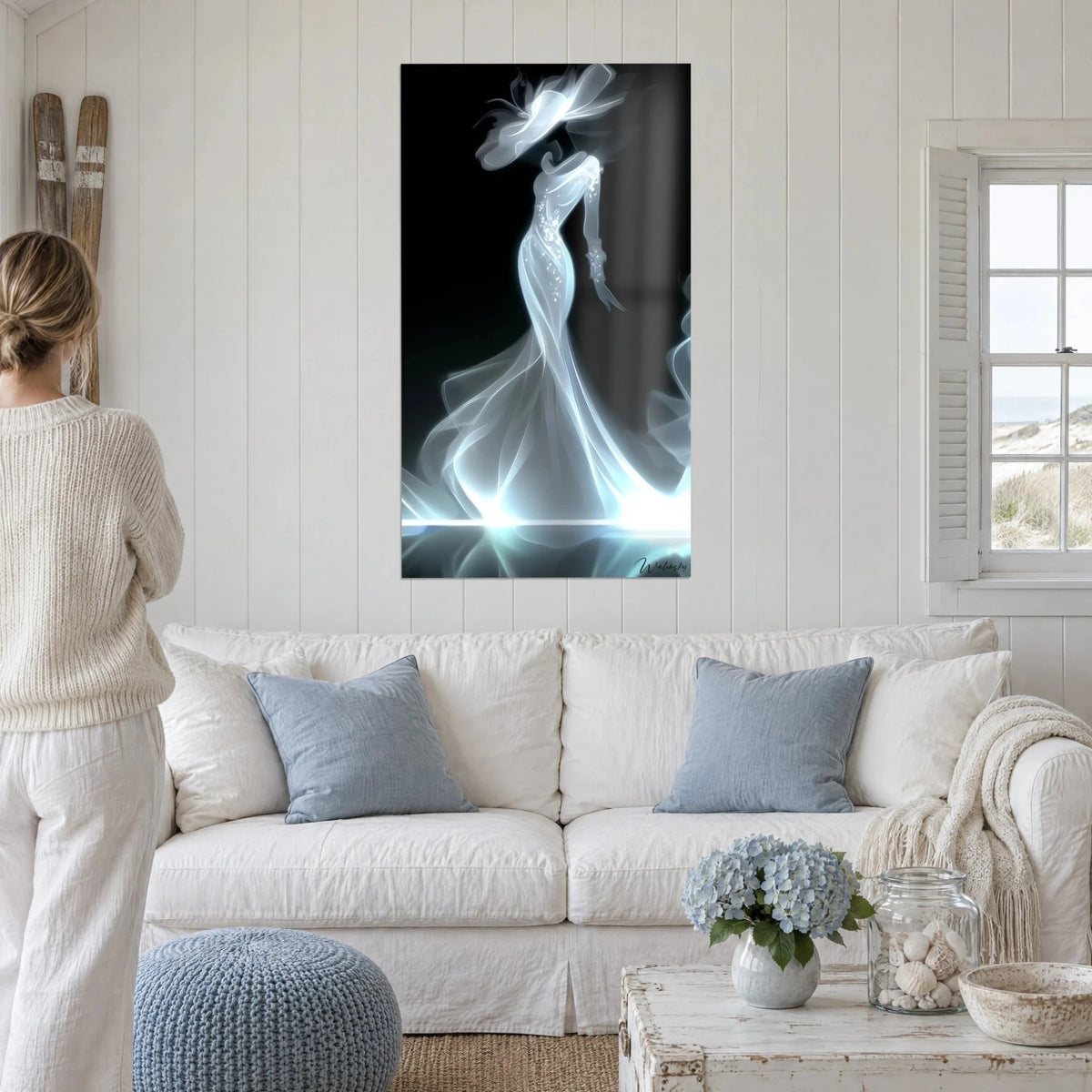 Quadro silhouette femminile in abito lungo di luce azzurrata, cappello fumé su fondo nero, sopra un divano in un soggiorno luminoso
