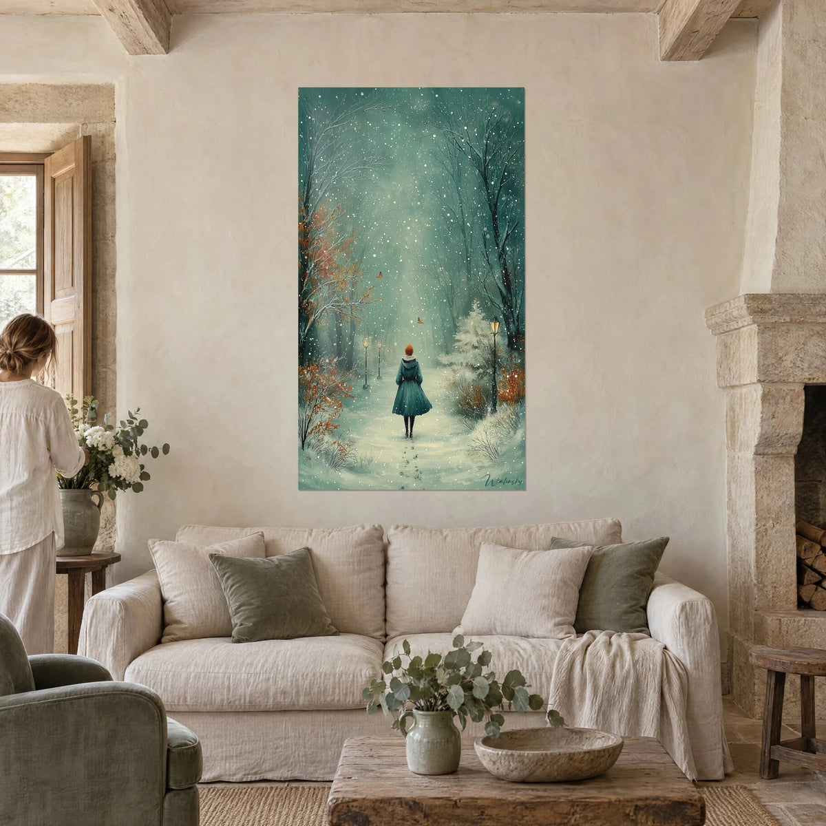 Tableau promeneuse encapuchonnée en bleu pétrole avançant sur un chemin neigeux, accroché au-dessus d'un canapé dans un salon lumineux