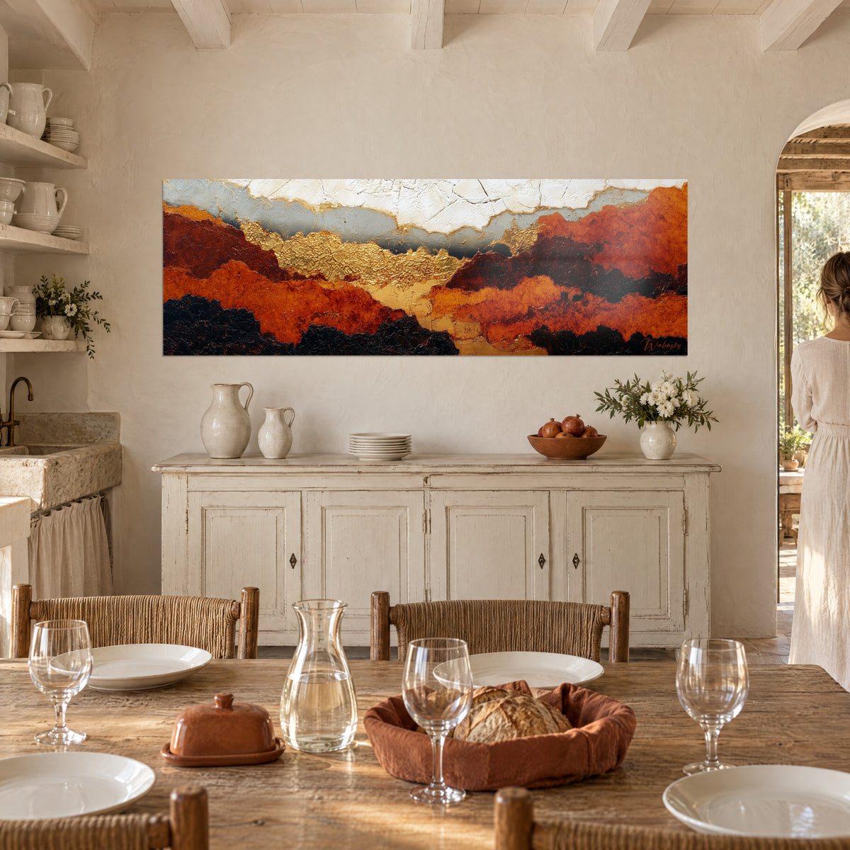 Wall art copper reliefs under a grey and white sky, person seen from behind near a white sideboard in a Provençal farmhouse