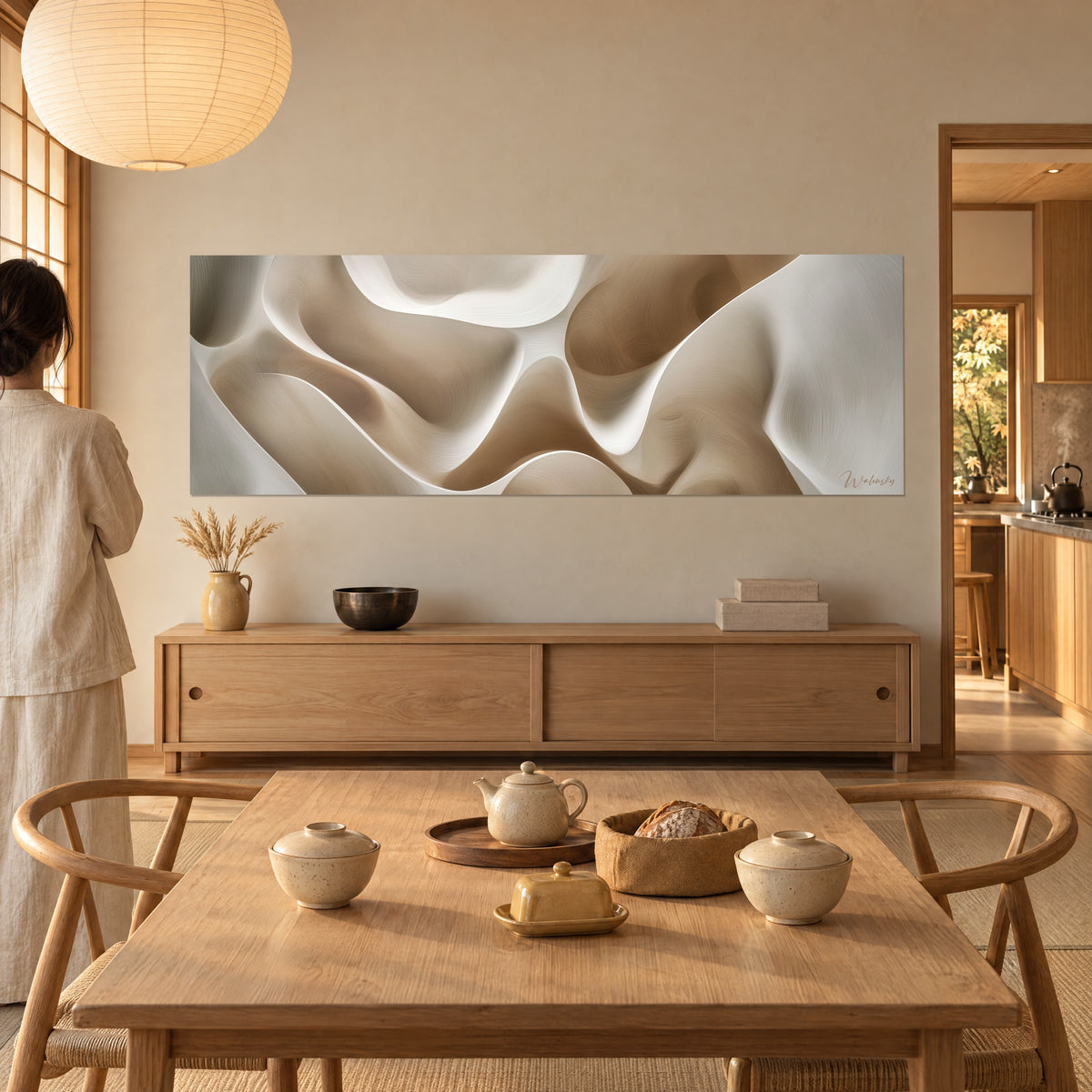 Quadro con scultura fluida in rilievi crema e marrone chiaro, una donna di spalle lo contempla, accanto a un tavolo in legno e a una teiera