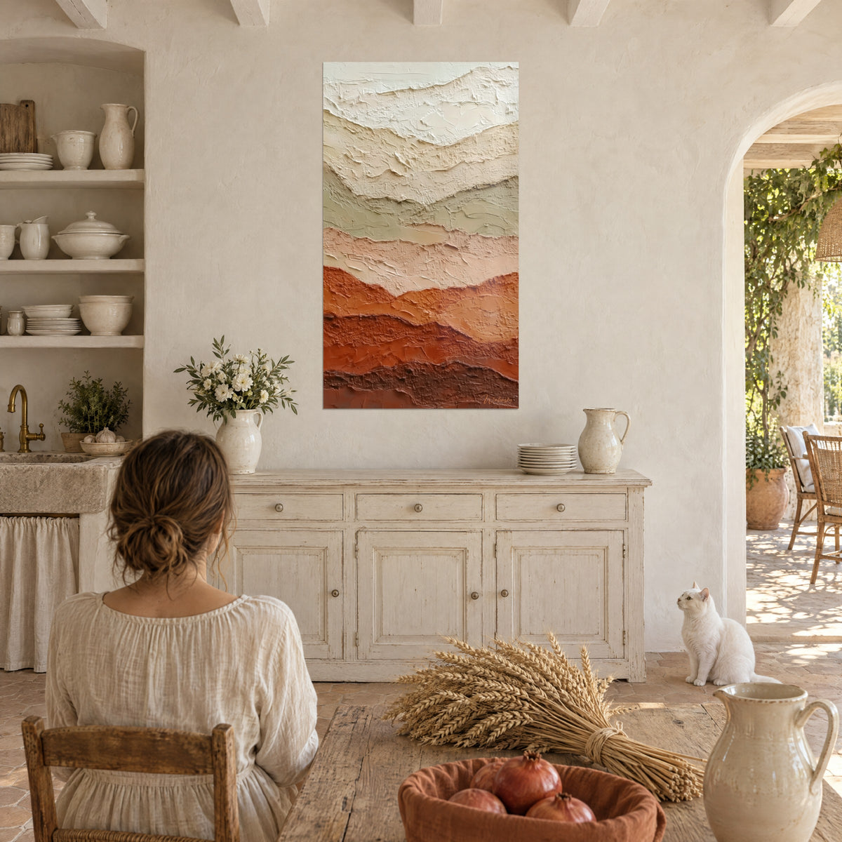 Wall art with mountains in palette-knife painting, off-white and brick red, a white cat sits near the sideboard