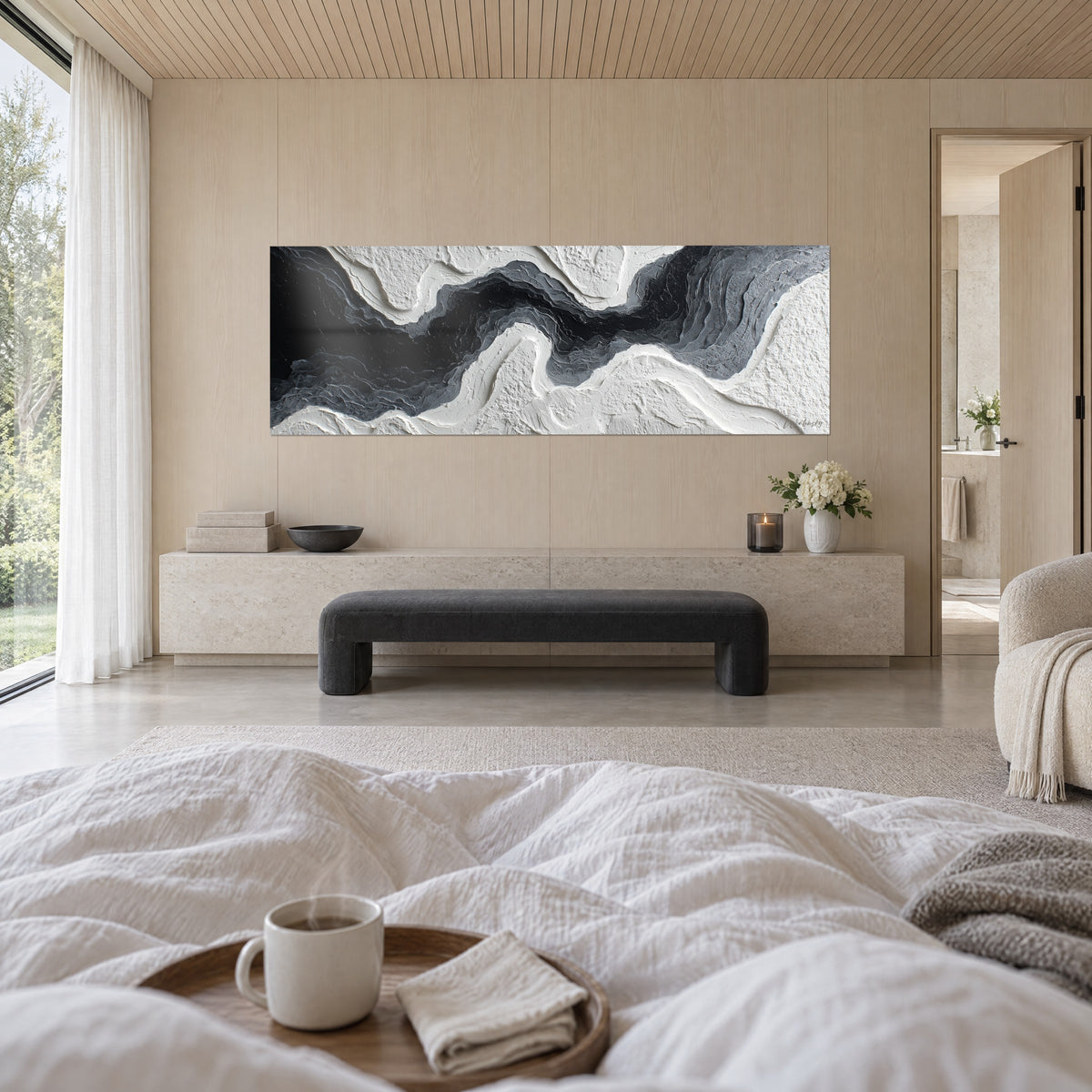 Cuadro de una cinta de tinta negra bordeada de capas grises sobre yeso blanco texturizado, sobre una cama en un dormitorio luminoso
