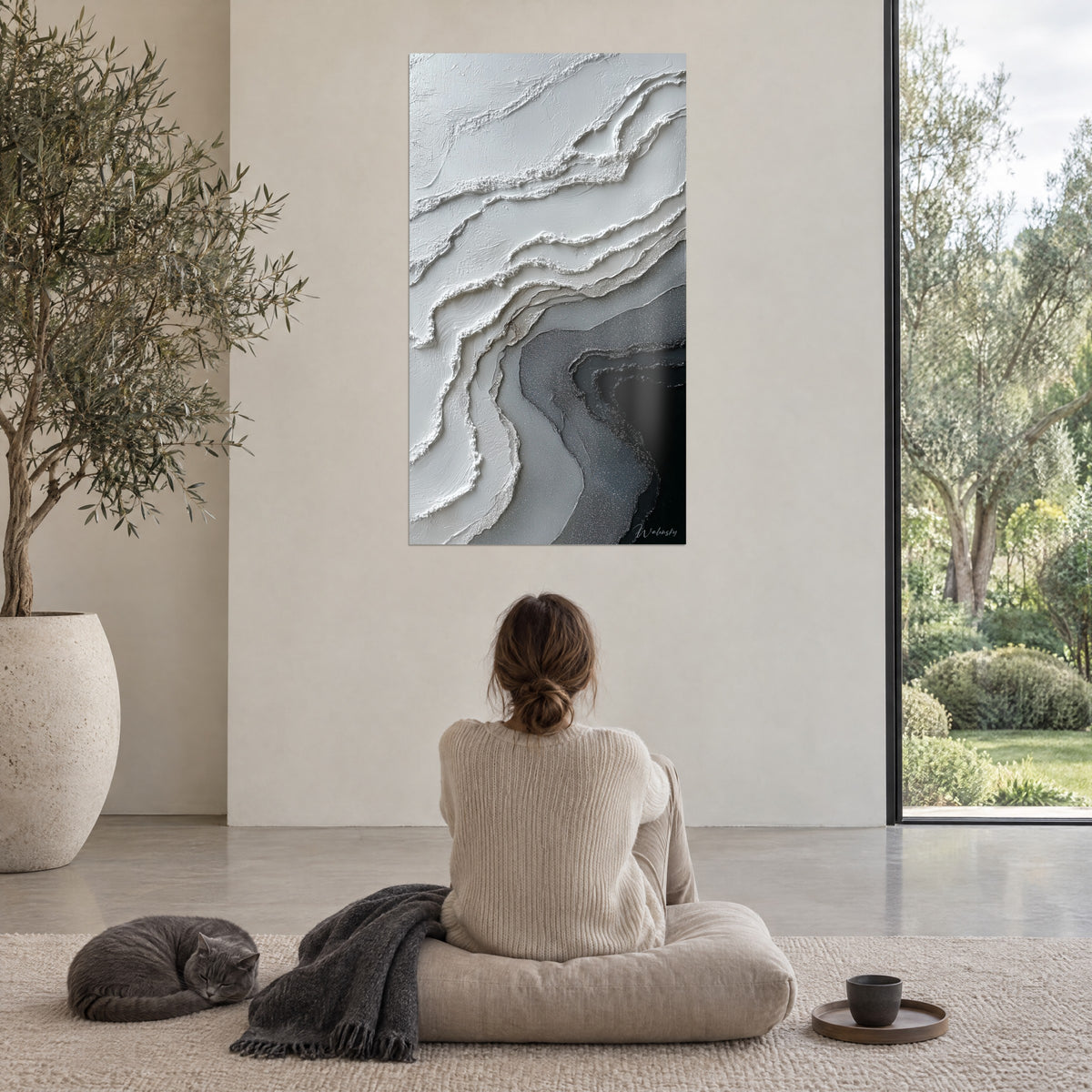 Quadro con paesaggio minerale astratto in avorio e nero profondo, ammirato da una donna seduta su un pouf, gatto a pelo corto grigio a riposo