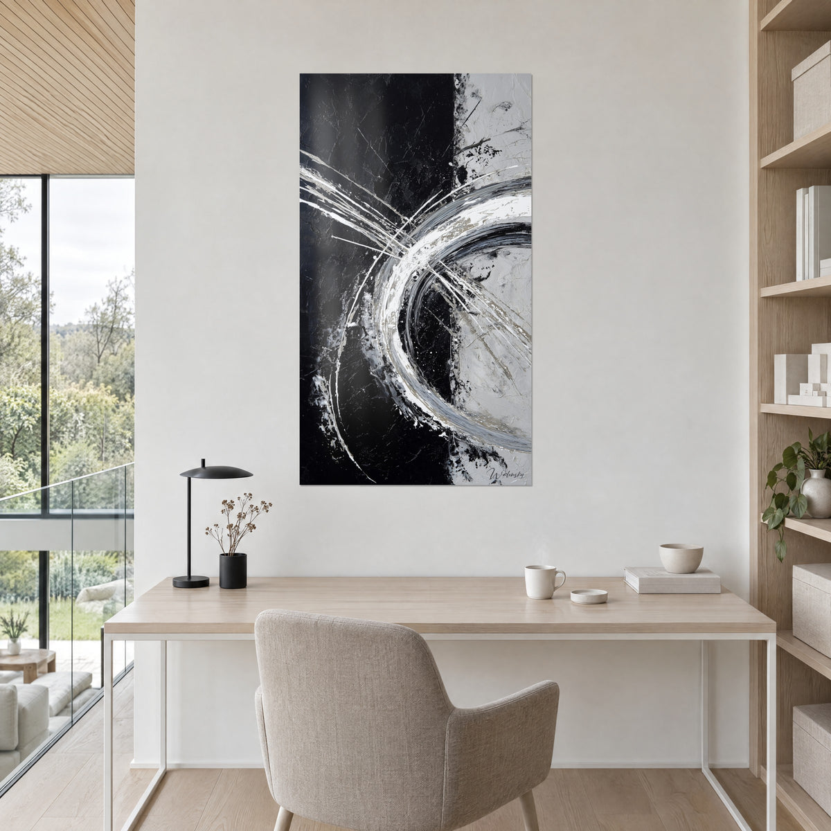 Quadro con cerchio di pittura spessa bianca e grigia tagliato da una linea nera verticale, sopra una scrivania in legno chiaro
