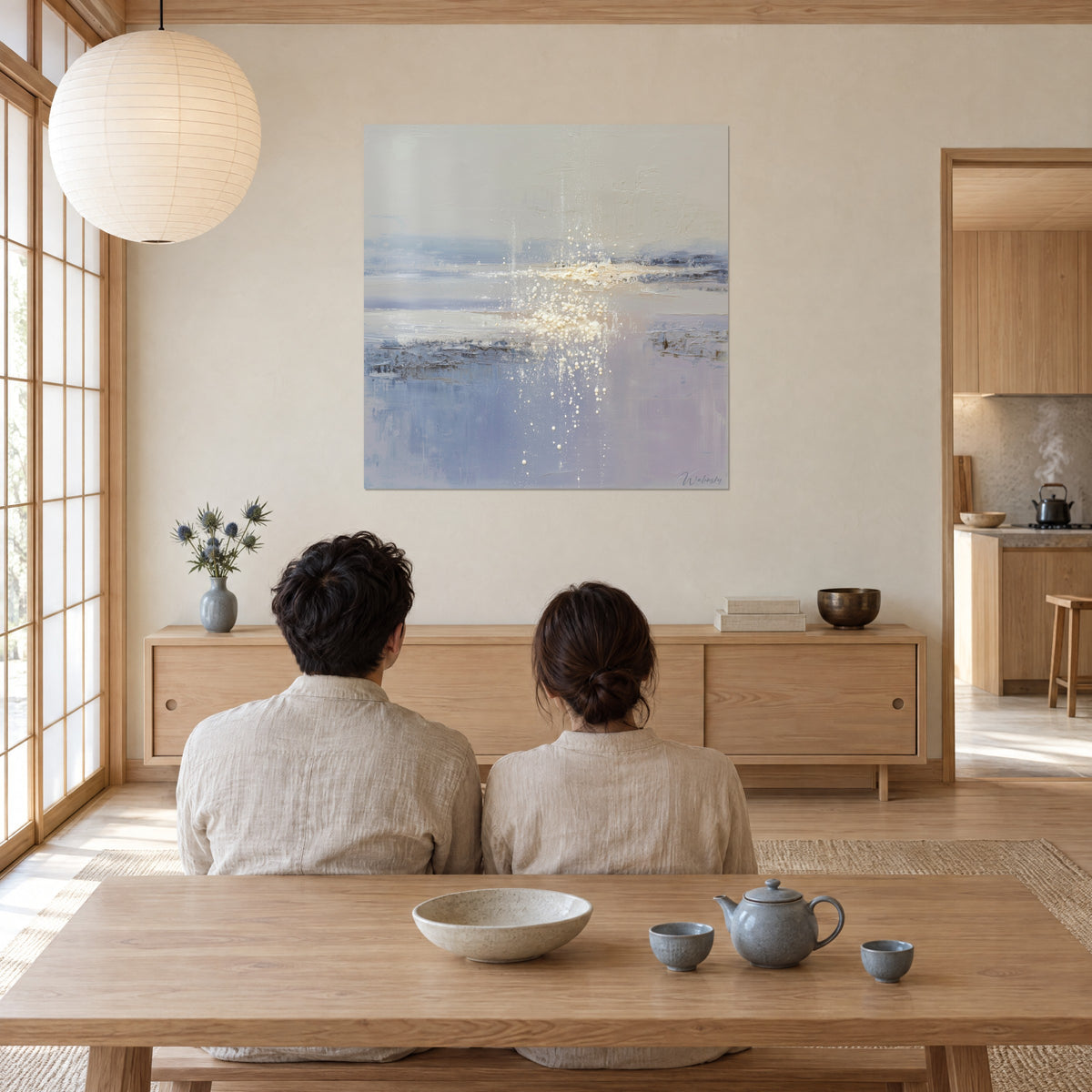 Cuadro orilla difuminada en azul acero y beige, lluvia de perlas doradas, pareja de espaldas sentada frente a un té, sala japandi