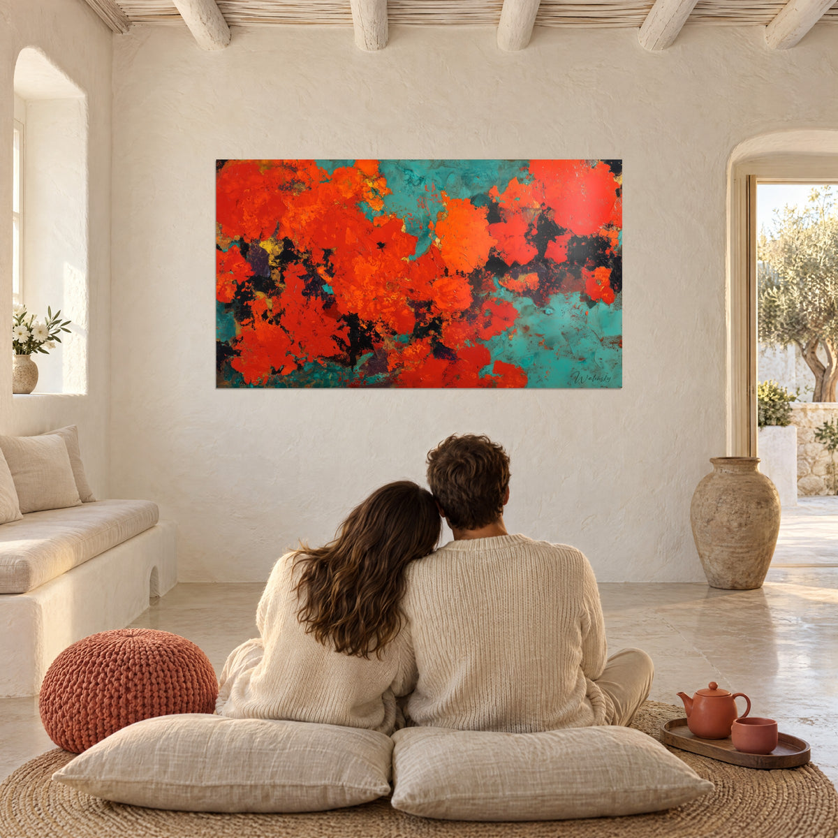 Schilderij laaiend oranje en koperkleurig turquoise, tegenover een koppel dat op kussens zit in een witte woonkamer