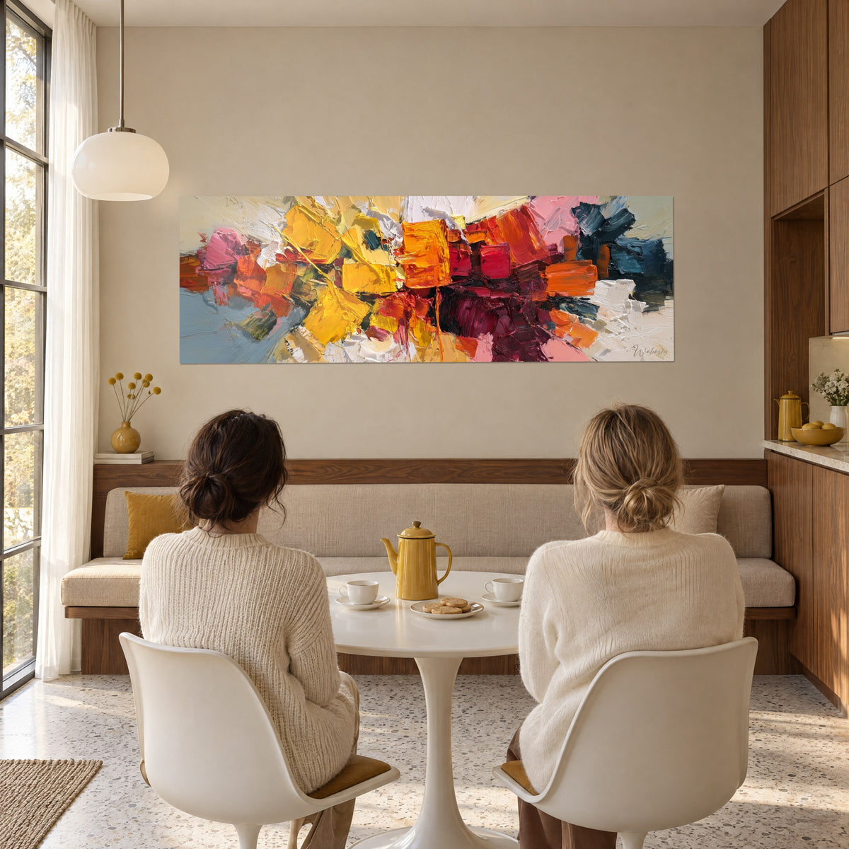 Cuadro bloque de energía amarillo sol y rojo intenso, toques azul petróleo a la derecha, frente a dos amigas sentadas a la mesa de un salón
