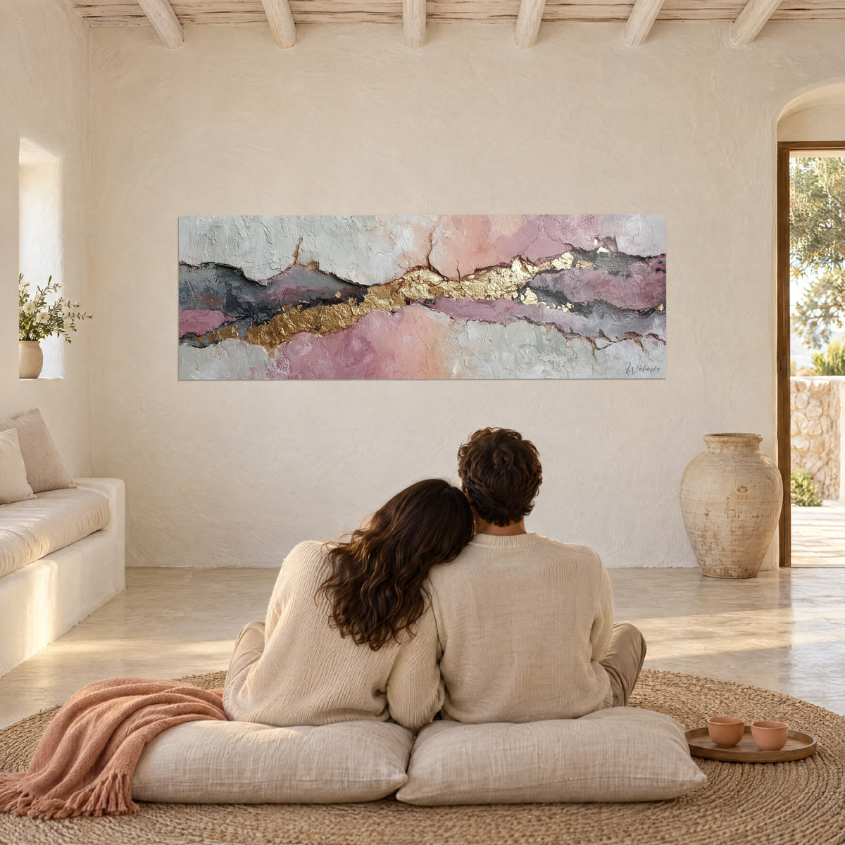 Cuadro de pareja de espaldas sentada sobre cojines beige, manta terracota, abstracto en marfil, malva y rosa con una cinta dorada en relieve