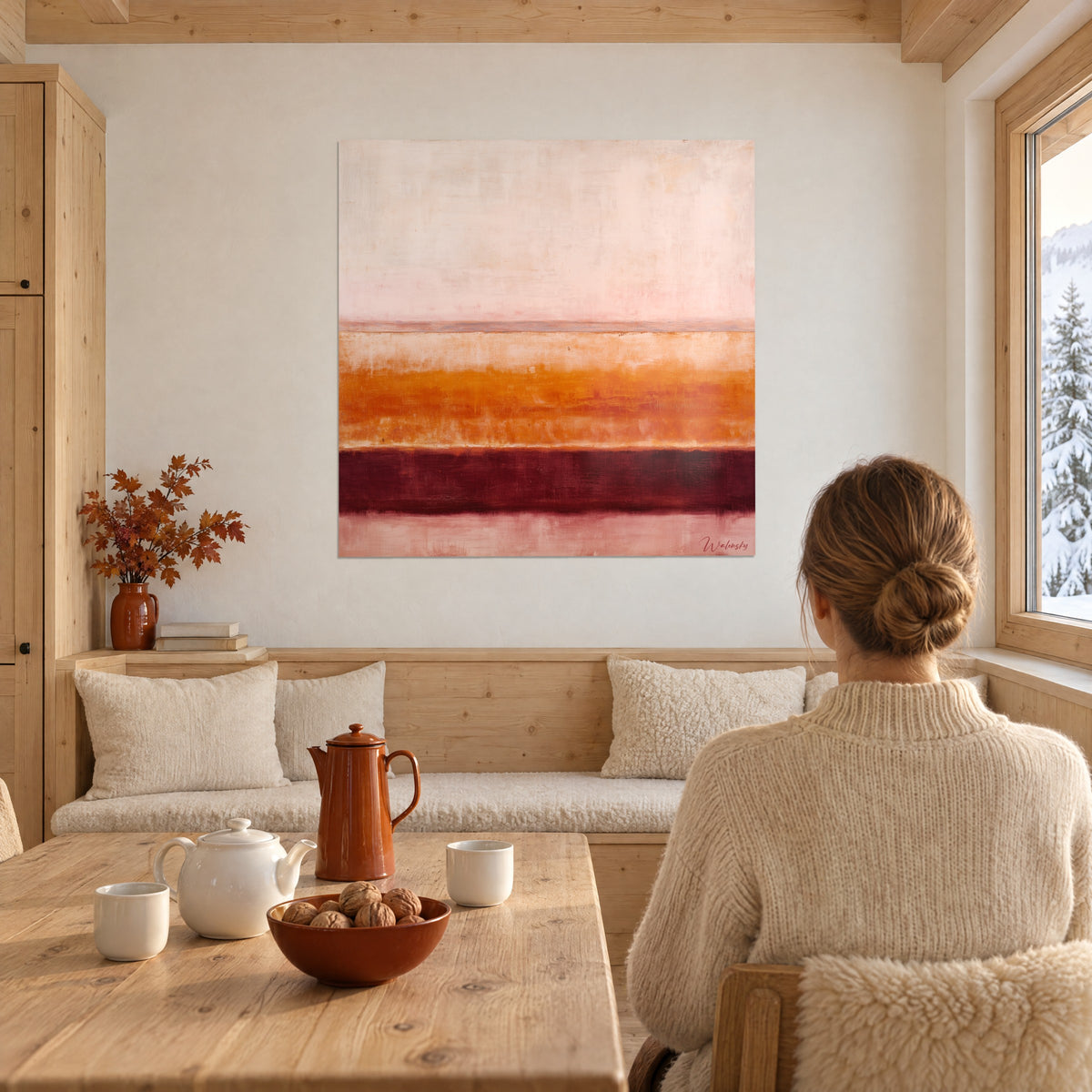 Wall art stacked horizons in creamy rose, saffron orange and garnet, a woman seen from behind in an ivory sweater in a chalet facing snowy mountains