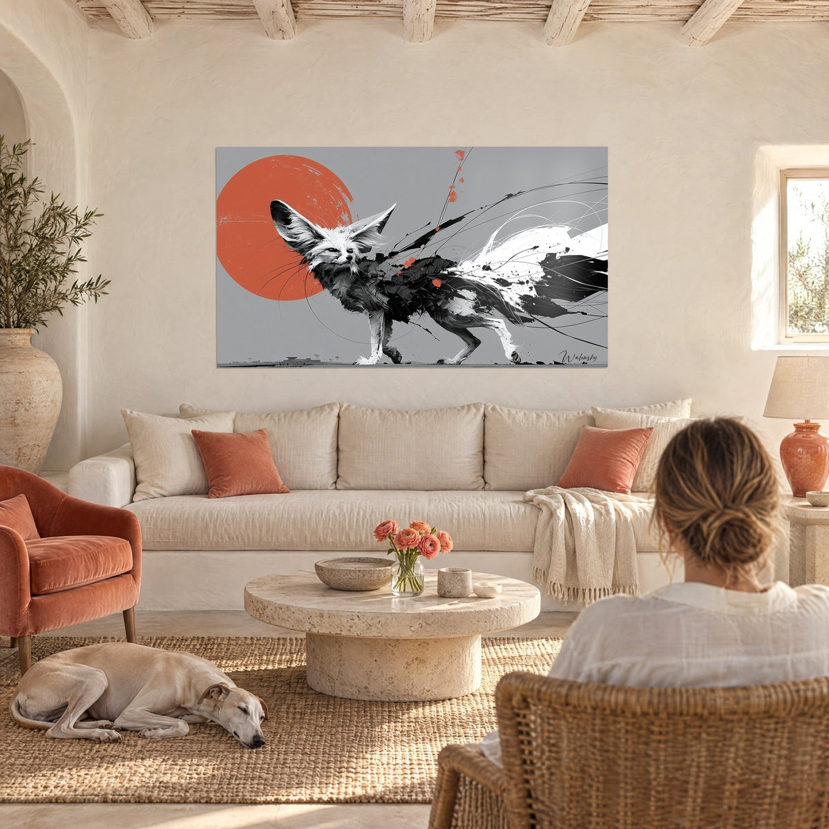 Quadro volpe fennec dalle grandi orecchie, disco arancione e tratti neri, una donna di spalle sopra un divano in un soggiorno luminoso