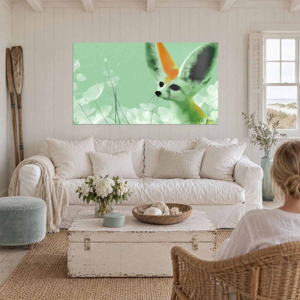 Wall art desert fox with huge green and orange ears on a sage green background, above a sofa in a bright living room
