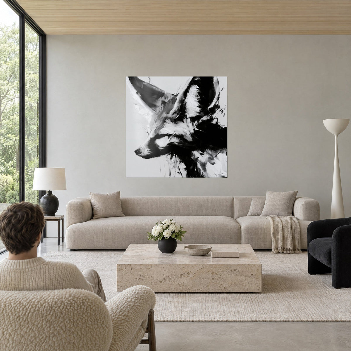 Wall art of a desert fox with large ears in black and white, smoky grey brushstrokes, above a sofa in a bright living room