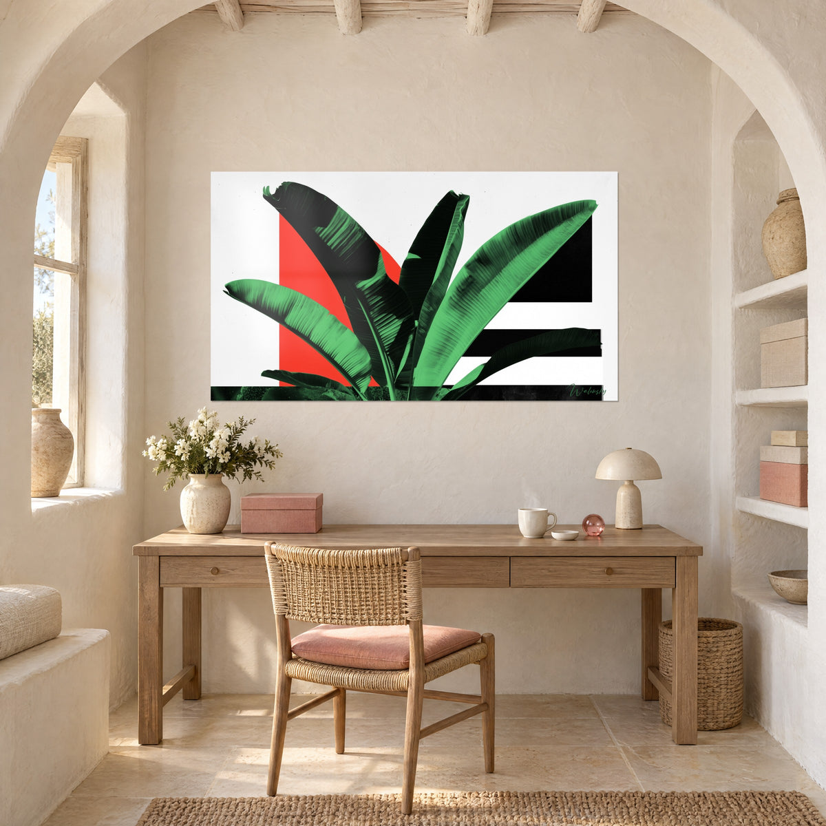 Tableau nature graphique aux palmes vert menthe et noires, pavé rouge et bandes ébène, au-dessus d'un bureau en bois clair