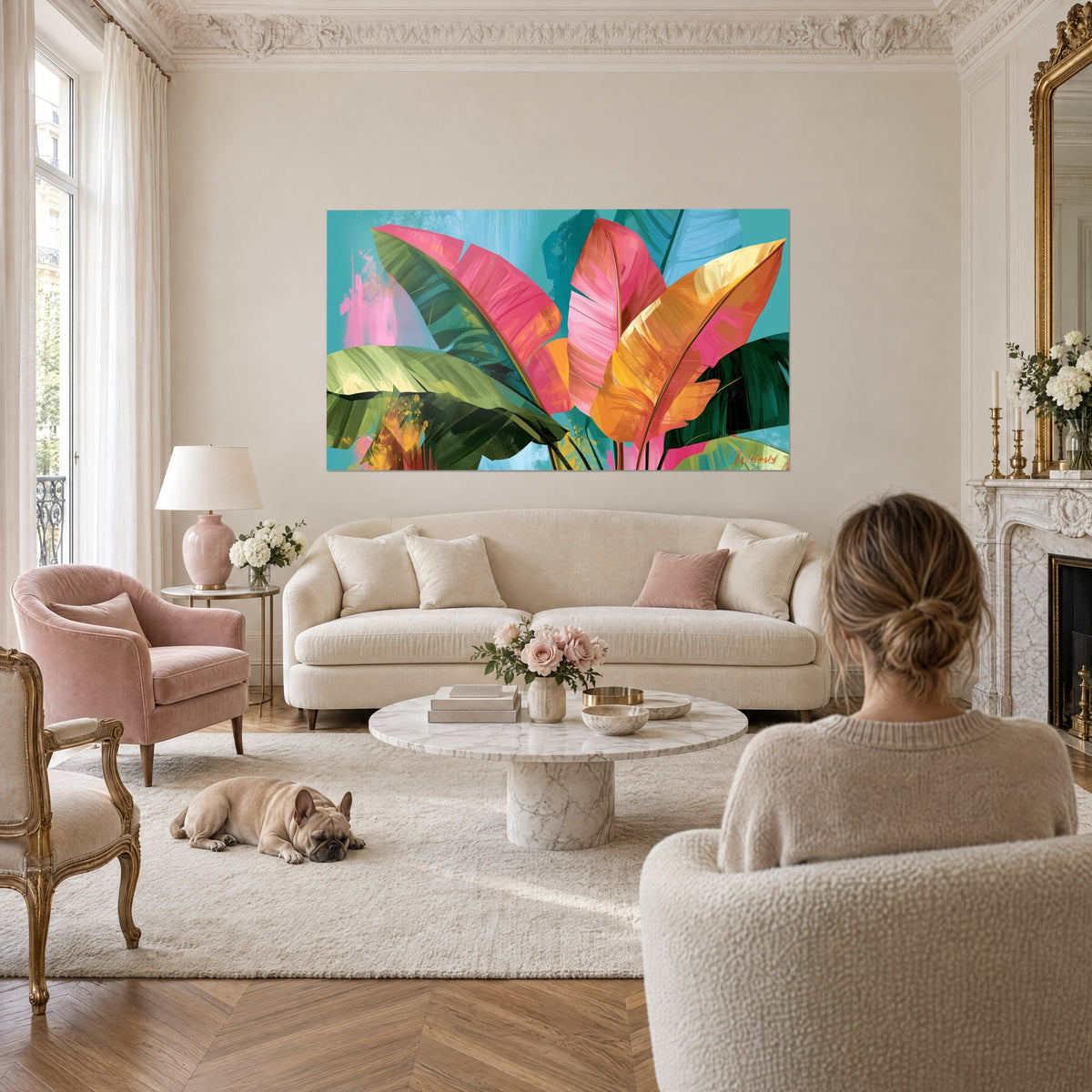 Tableau feuilles de bananier roses et dorées sur fond turquoise, femme de dos et bulldog, au-dessus d'un canapé dans un salon lumineux