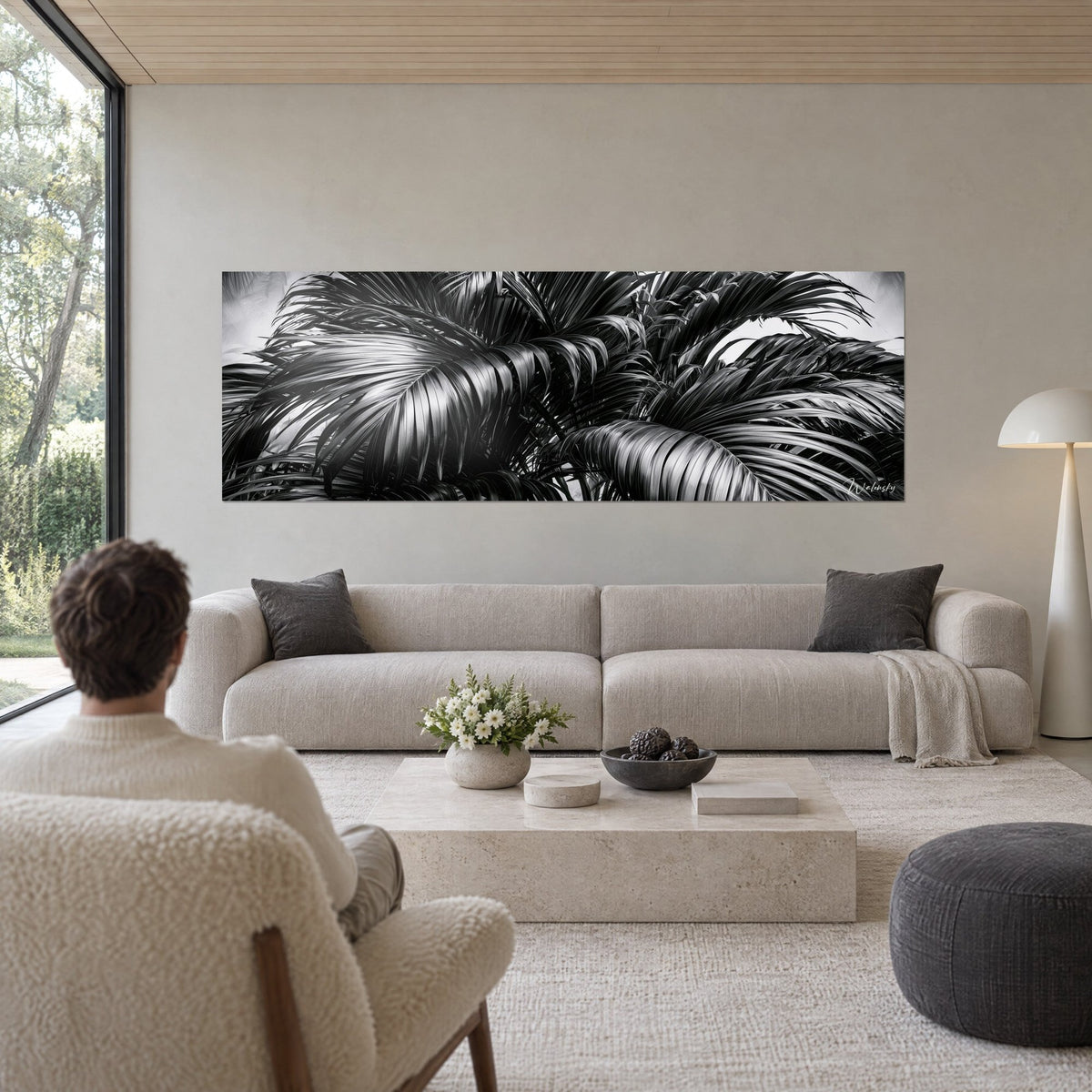 Wall art black and white palm fronds, glossy silver leaves on a pearl grey background, above a sofa in a bright living room