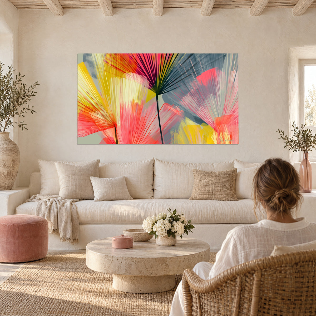 Wall art of a fan palm with coral pink and lemon yellow fronds on a grey background, hung above a sofa in a bright living room