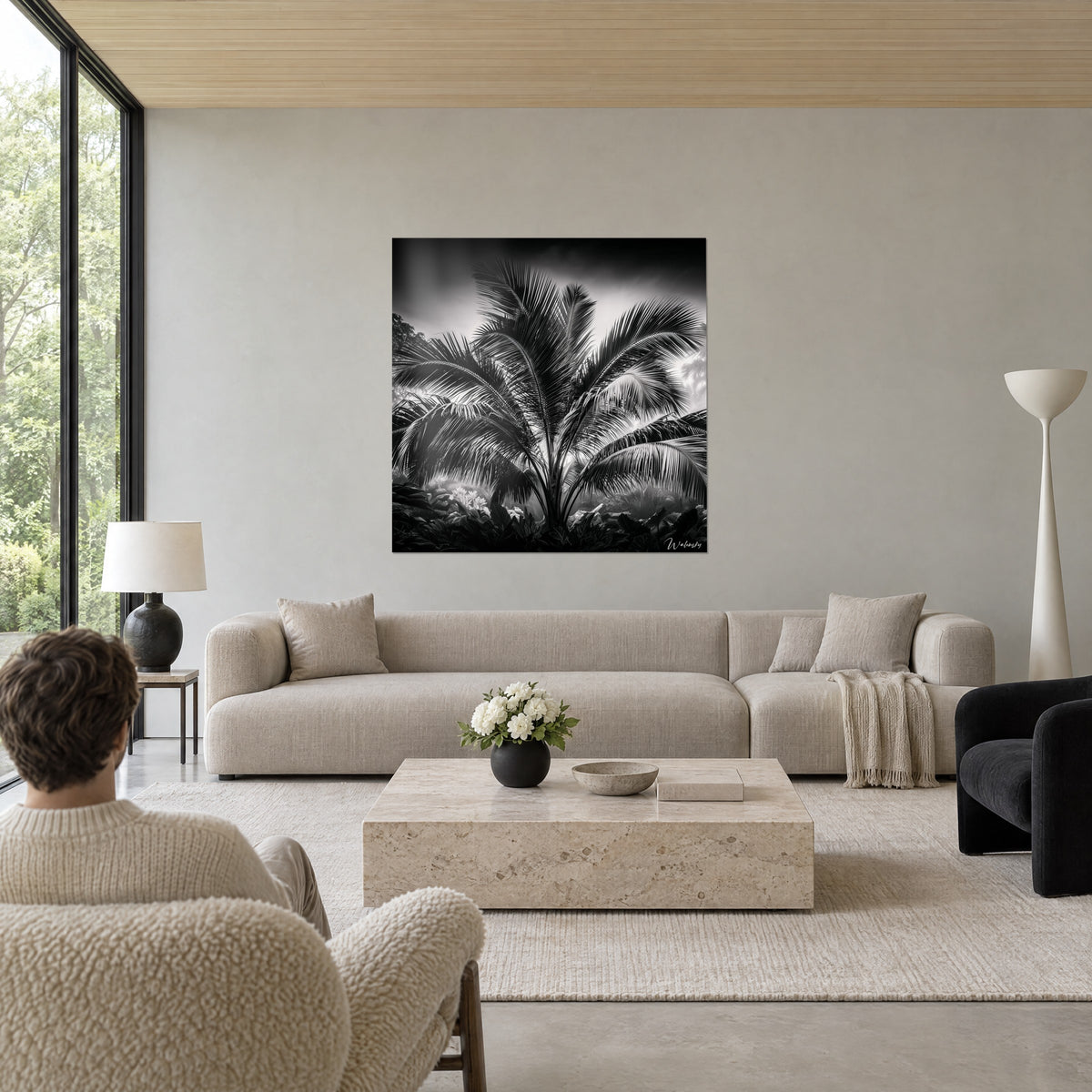 Wall art black and white palm tree, silvery fronds against a misty grey sky, hung above a sofa in a bright living room