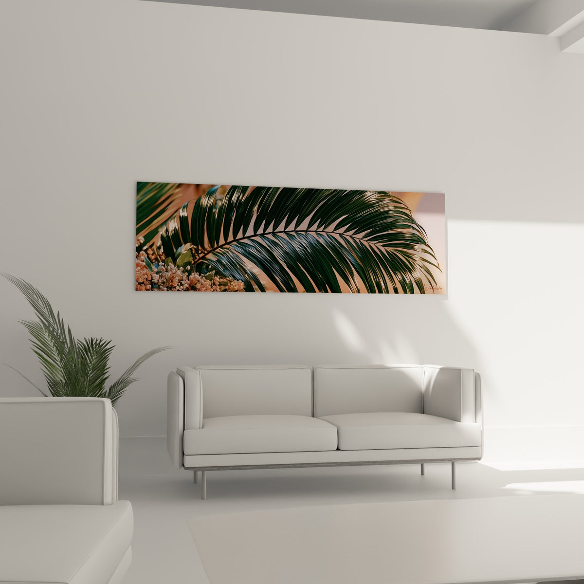 Feuillage vert émeraude et fleurs beige dorées, disposé au-dessus d'un canapé dans un salon lumineux