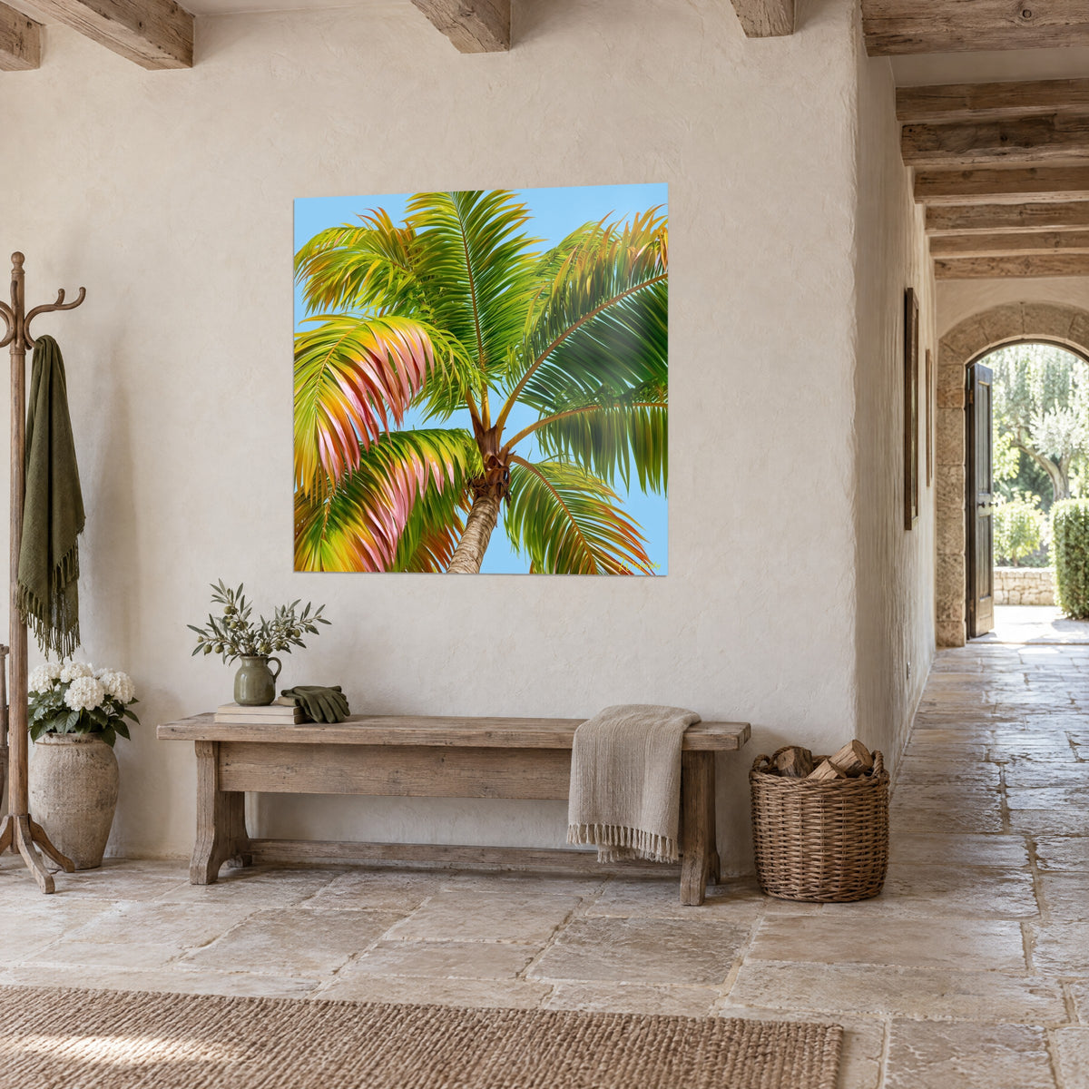 Coconut palm wall art seen from below, golden yellow and soft pink fronds against a blue sky, at the back of an old stone entrance
