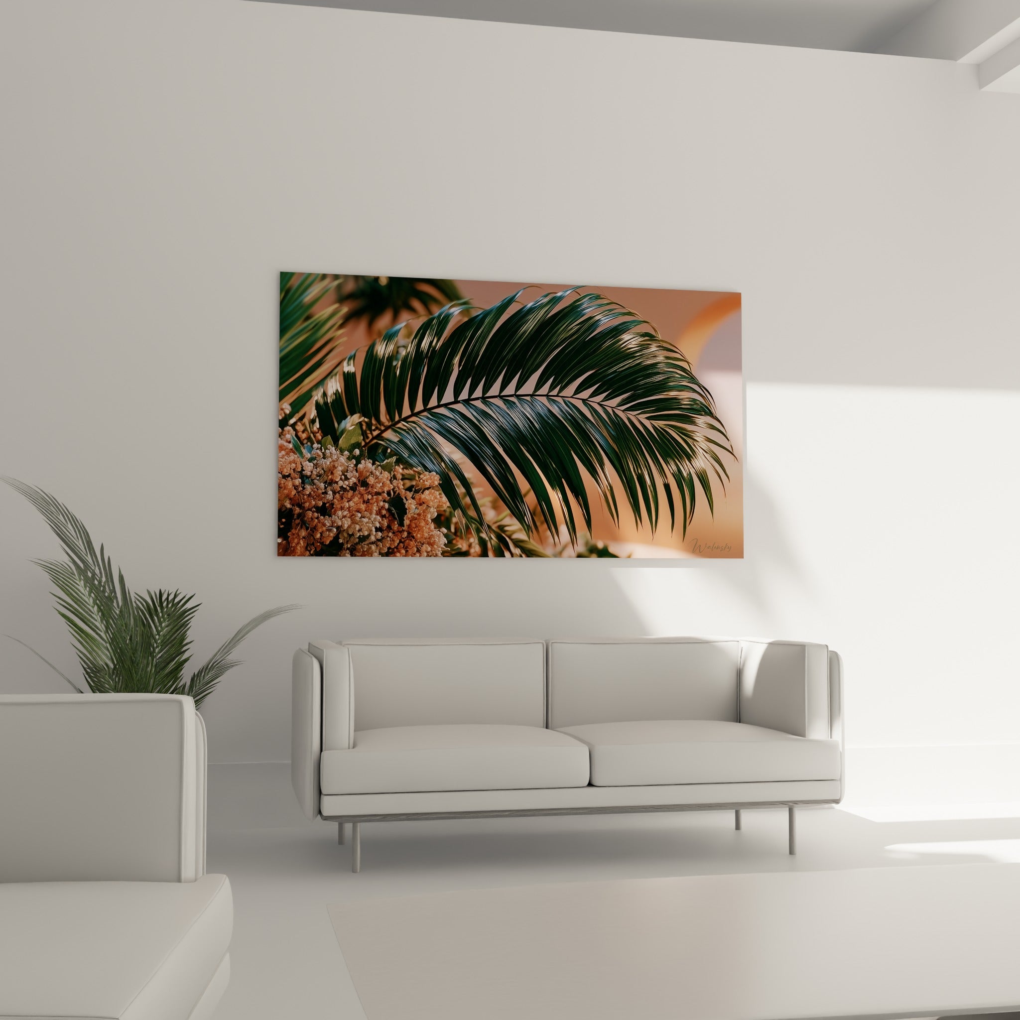 Feuille de palmier vert sombre et fleurs terracotta accrochée au-dessus d'un canapé dans un salon lumineux