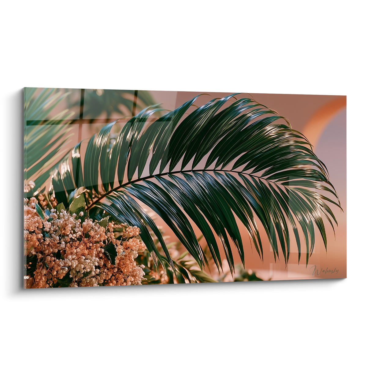 Feuille de palmier vert profond déployée devant un fond terracotta et fleurs séchées ocre