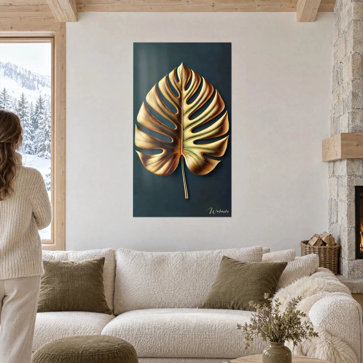 Tableau feuille de monstera dorée aux nervures ciselées sur fond bleu nuit, au-dessus d'un canapé dans un salon lumineux