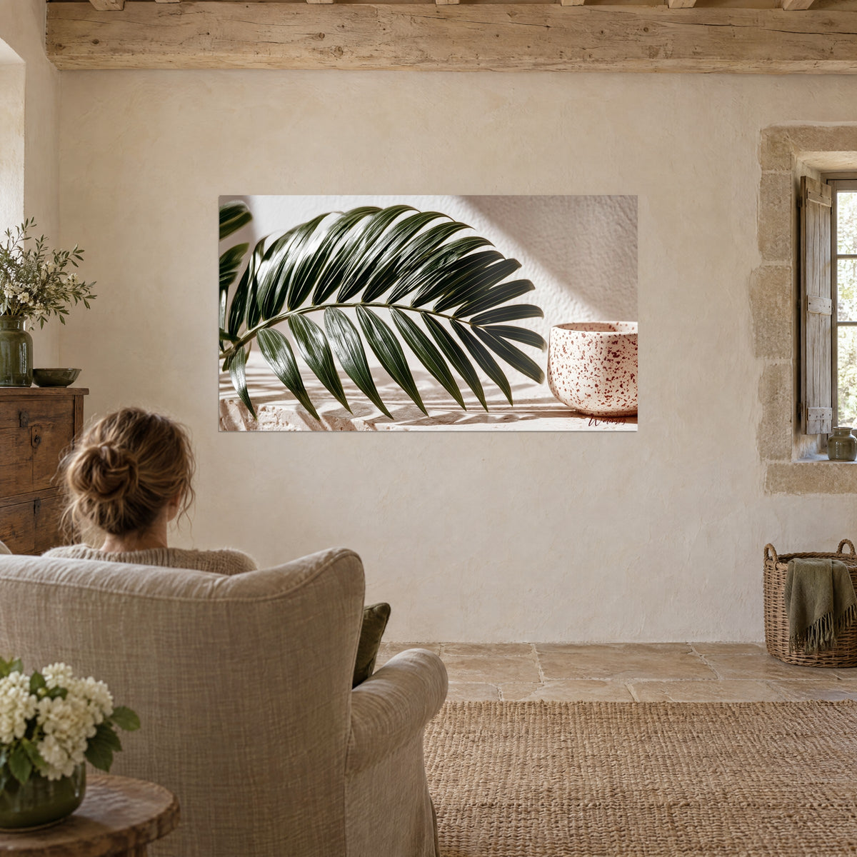 Schilderij palm met donkere waaiervormige blaadjes, romig beige en baksteen achtergrond, voor een linnen fauteuil in een woonkamer