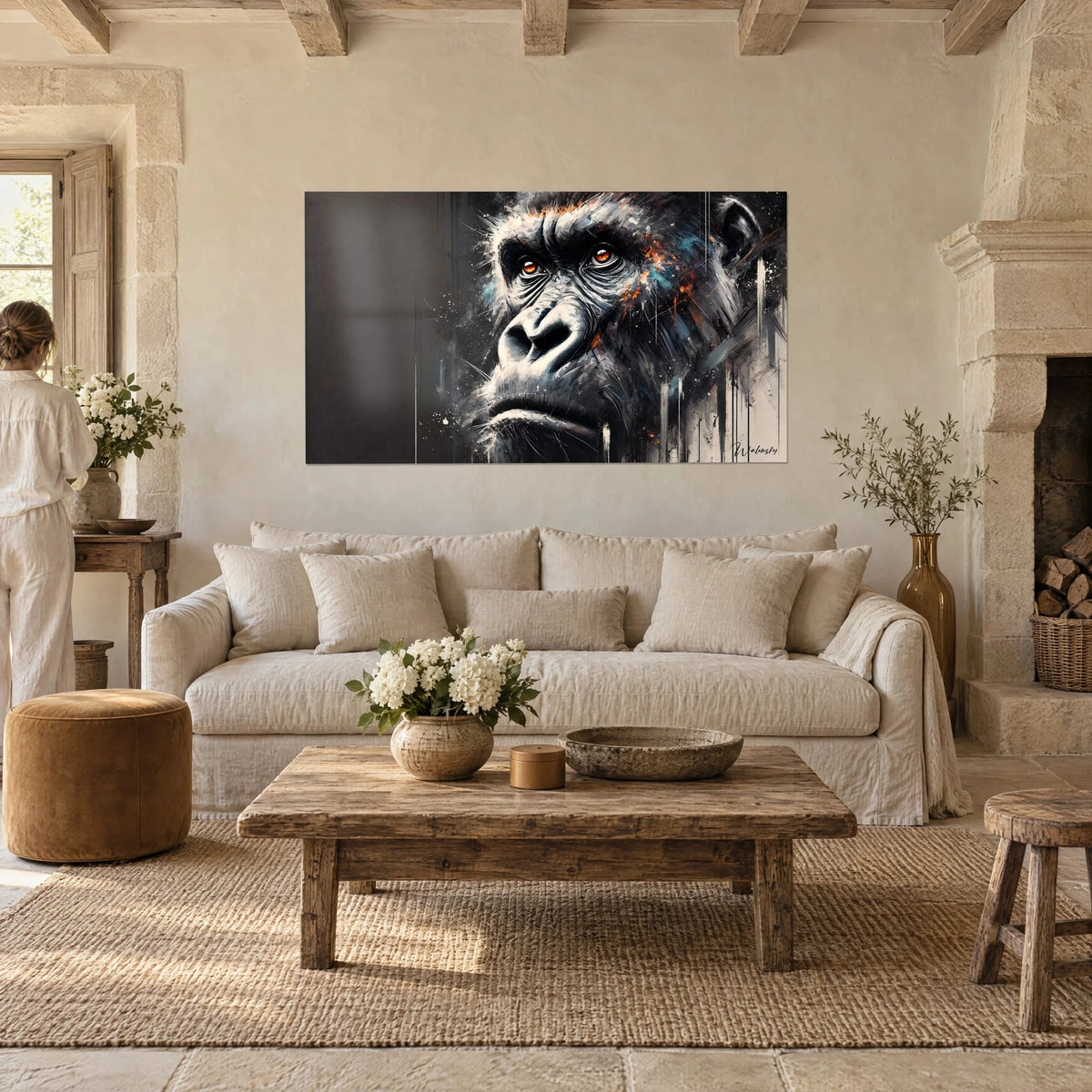Wall art gorilla with amber eyes, black fur with orange and blue traces, hung in a stone living room above a sofa in a bright lounge