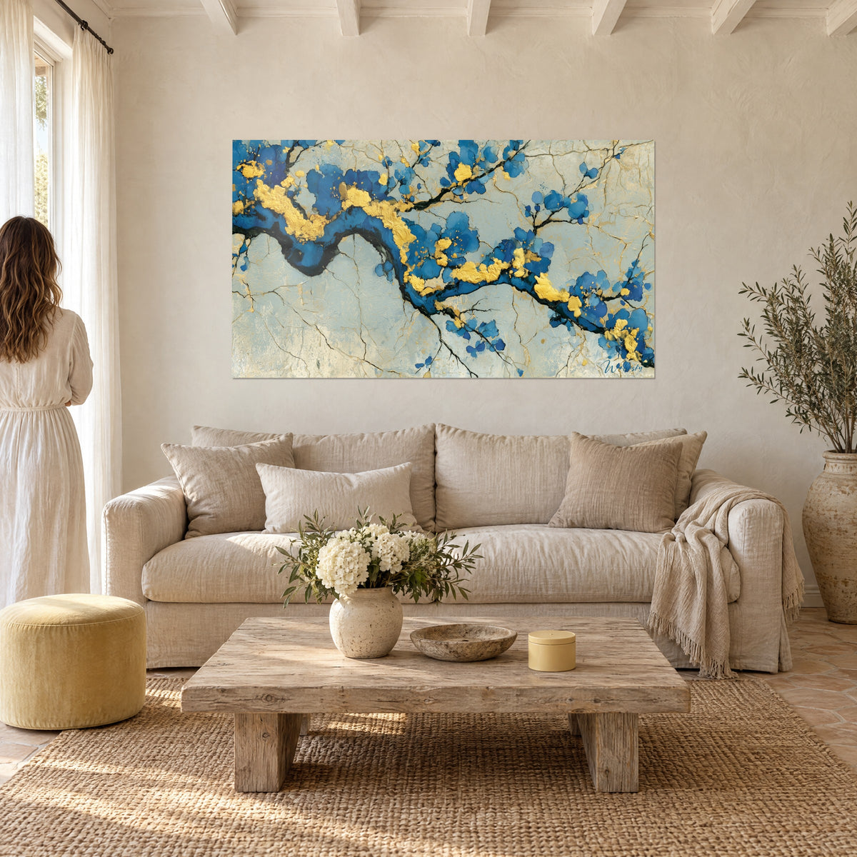 Πίνακας με κλαδί λουλουδιών σε κομπαλτί μπλε και χρυσό φύλλο, αφηρημένα άνθη σε ραγισμένο φόντο, πάνω από καναπέ σε φωτεινό σαλόνι