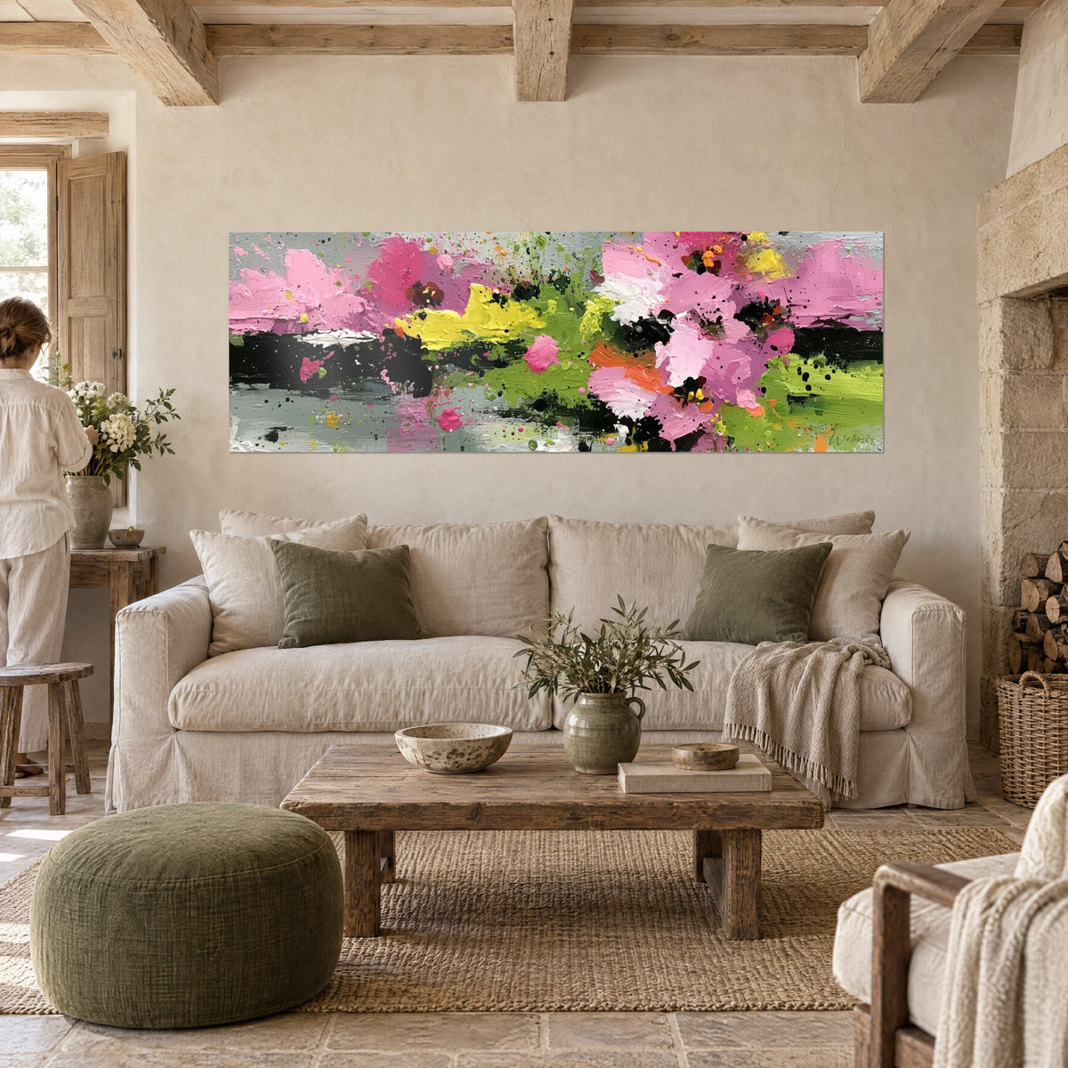 Cuadro flores abstractas rosas y verdes, destellos negros sobre fondo gris plateado, mujer de espaldas, encima de un sofá en un salón luminoso