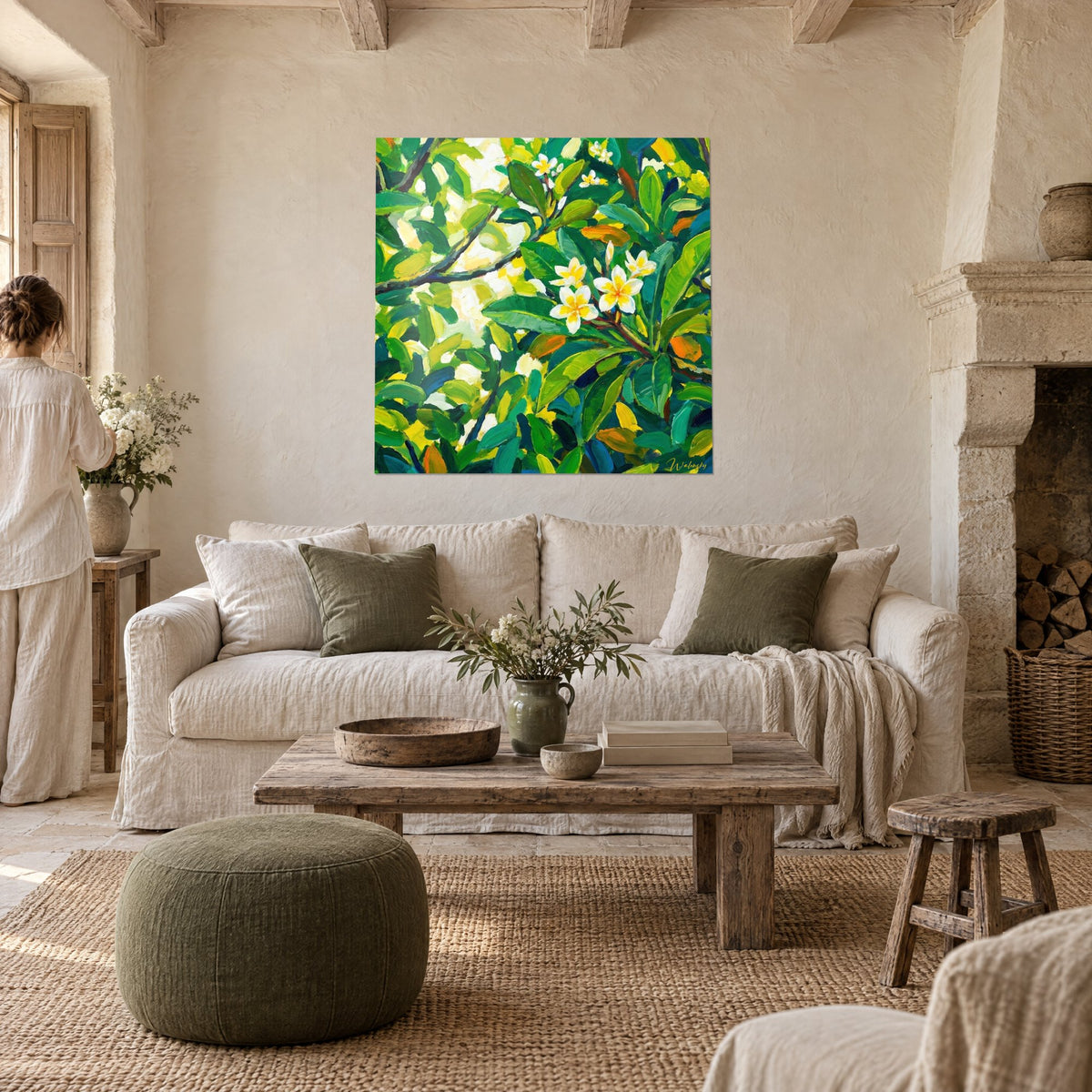Quadro fiore di frangipani dai petali bianchi e cuore giallo tra foglie verde smeraldo, sopra un divano in un soggiorno luminoso
