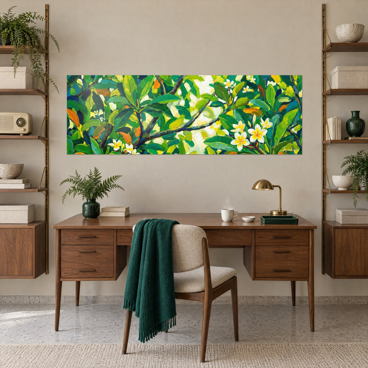 Tableau fleurs de plumeria blanches et jaunes dans un feuillage dense vert sapin, accroché au-dessus d'un bureau en bois