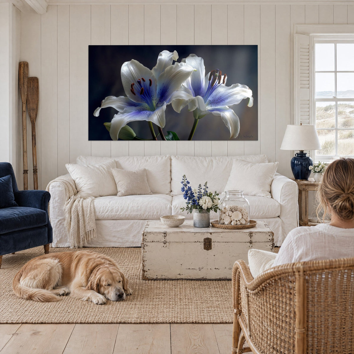 Schilderij twee witte lelies met indigoblauwe harten en koperkleurige meeldraden, liggende retriever, boven een bank in een lichte woonkamer