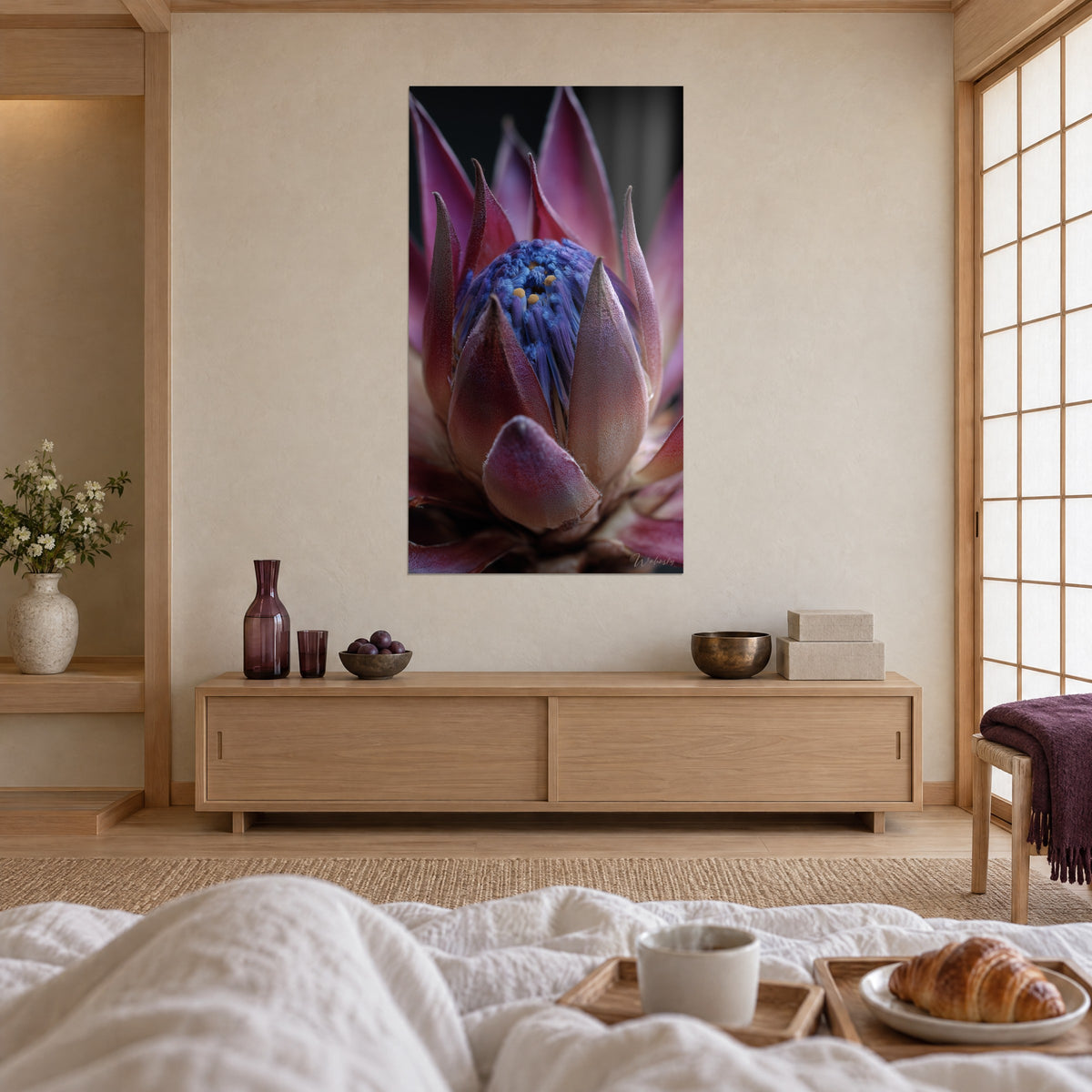 Tableau artichaut sauvage rose et bleu, pistils dorés sur fond noir, au-dessus d'un lit dans une chambre claire