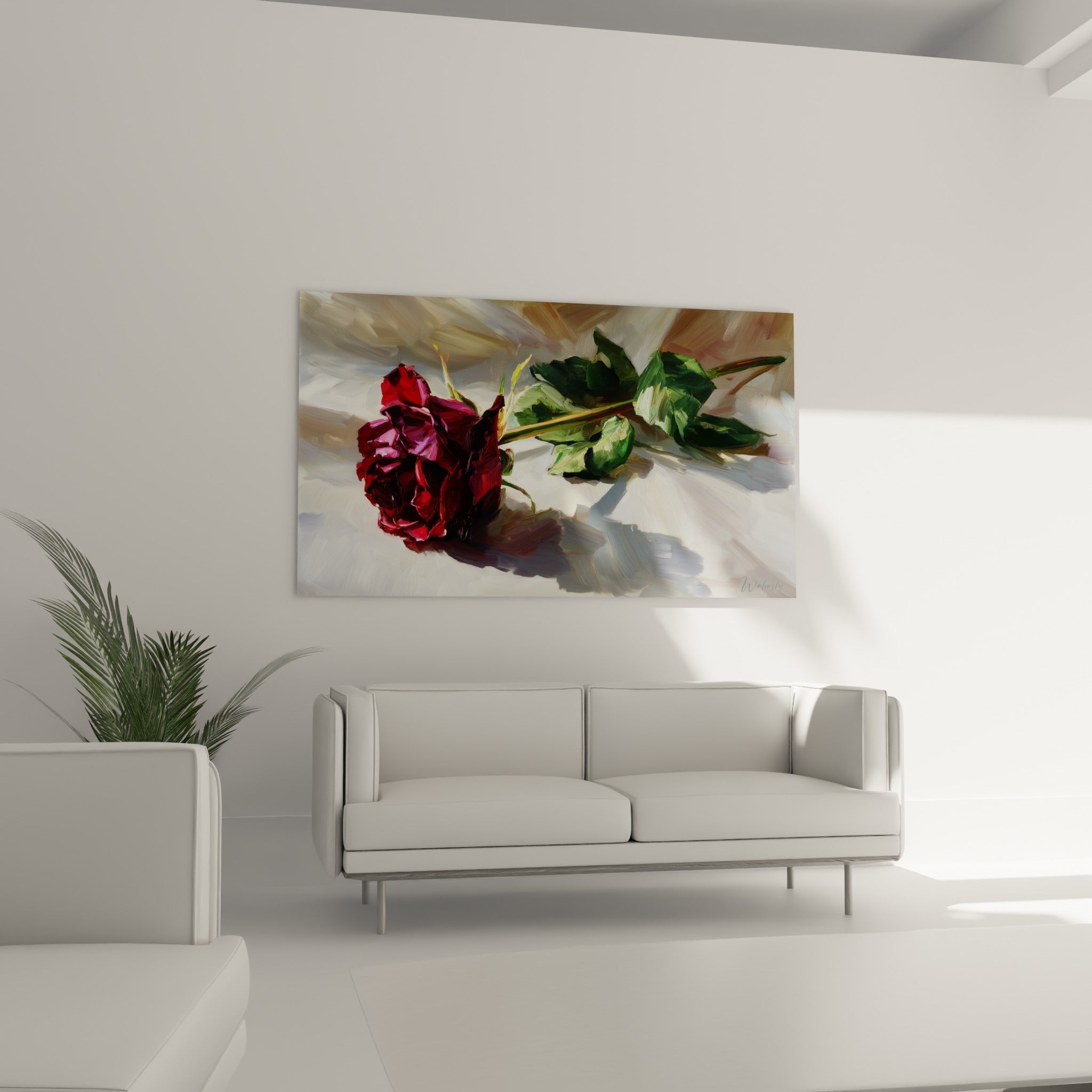 Tige verte et feuilles sombres accompagnant une rose rouge veloutée, au-dessus d'un canapé dans un salon lumineux