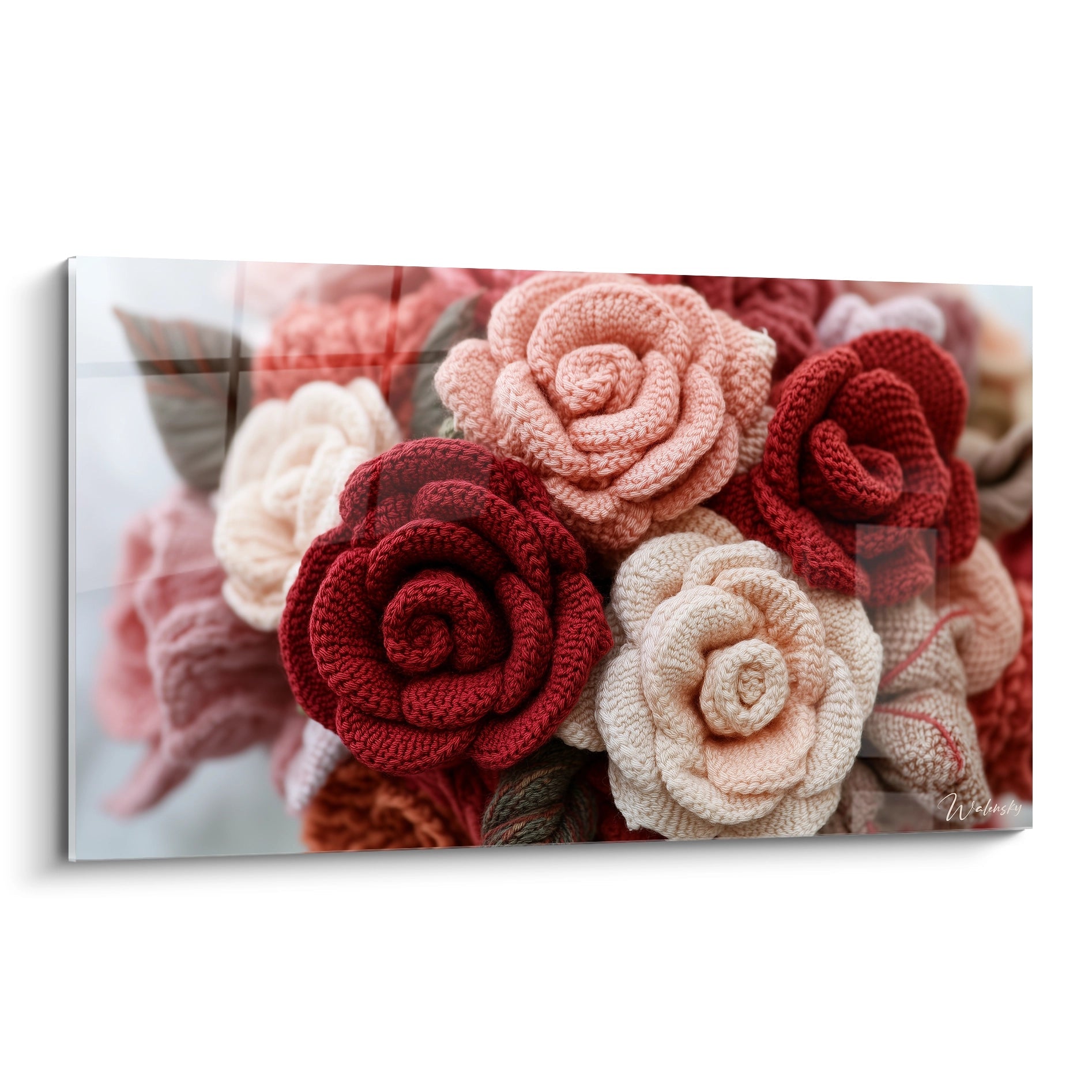 Un tableau artistique présentant des roses en crochet aux textures variées, avec des fleurs en relief rouge profond, rose poudré et blanc crème, formant un bouquet textile tridimensionnel sur fond neutre.
