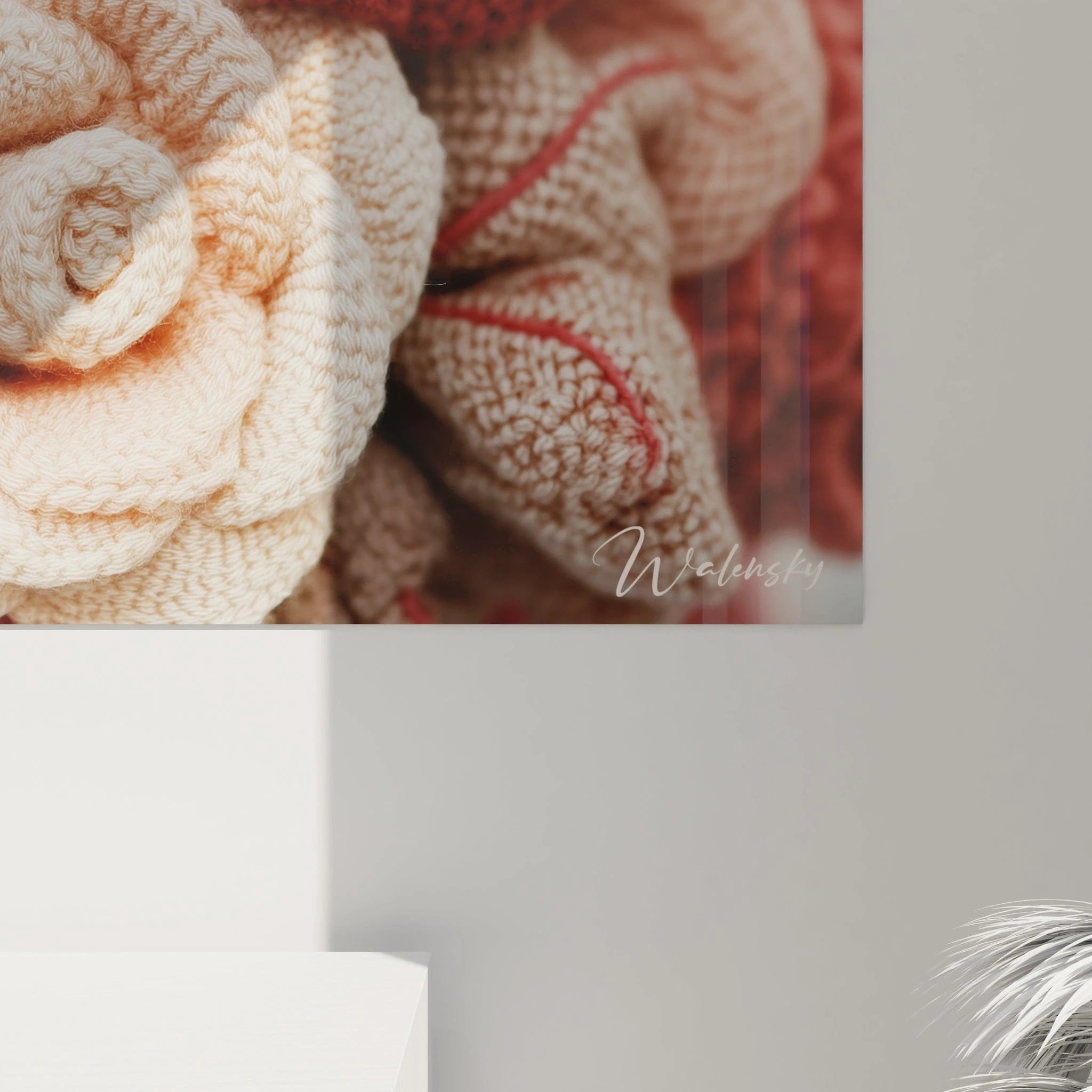 Un tableau textile affichant un bouquet de roses réalisées au crochet, mêlant harmonieusement des teintes de rouge profond, rose poudré et blanc crème, où chaque fleur présente des détails finement travaillés et une structure spiralée caractéristique.
