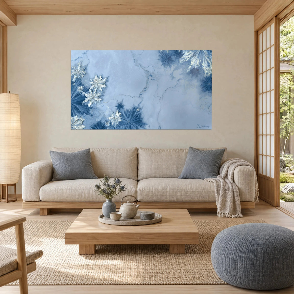 Wall art with white and navy snowflakes on a veined icy blue background, above a sofa in a bright living room